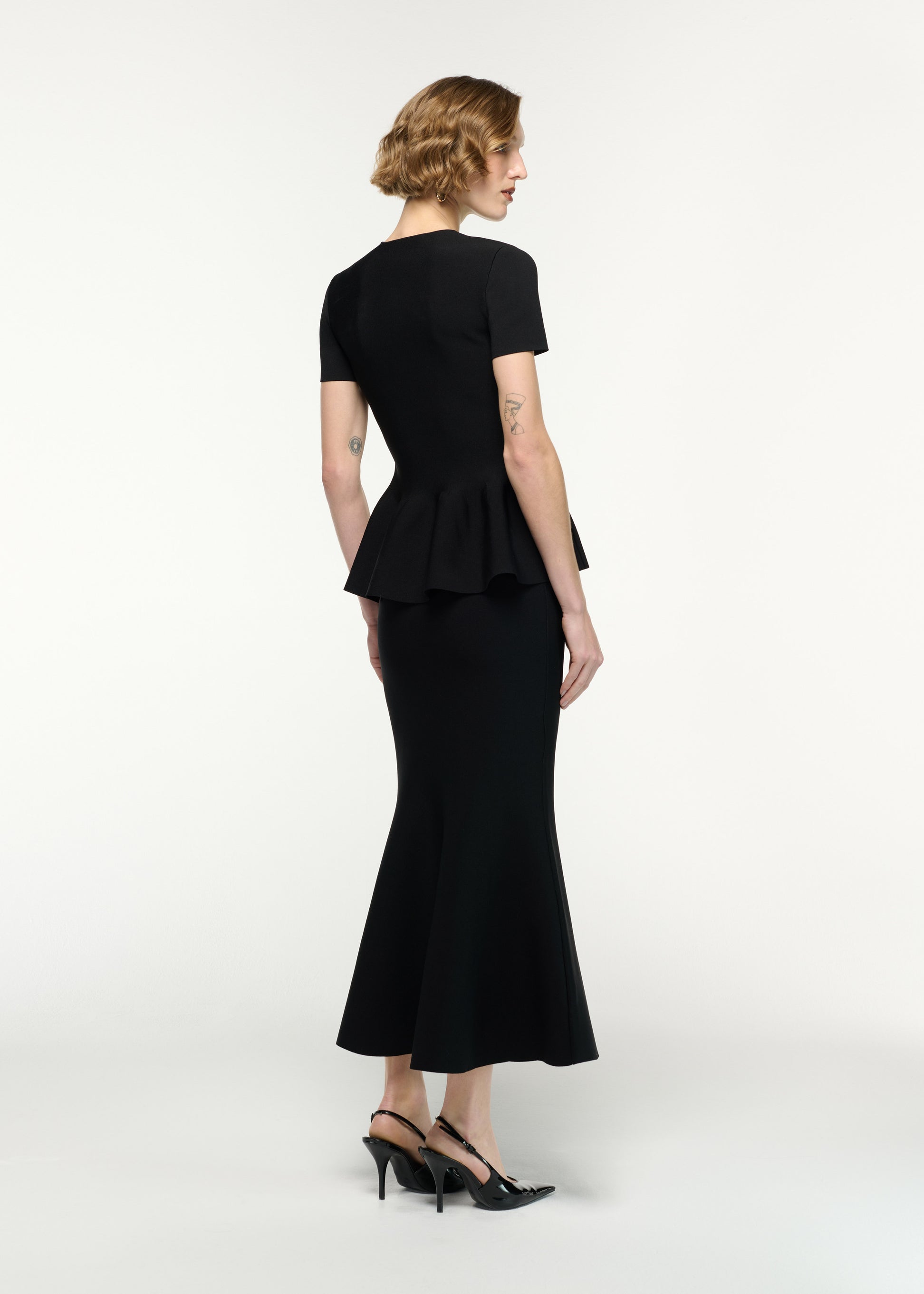 Back view of a model wearing the Mermaid Knit Midi Skirt in Black