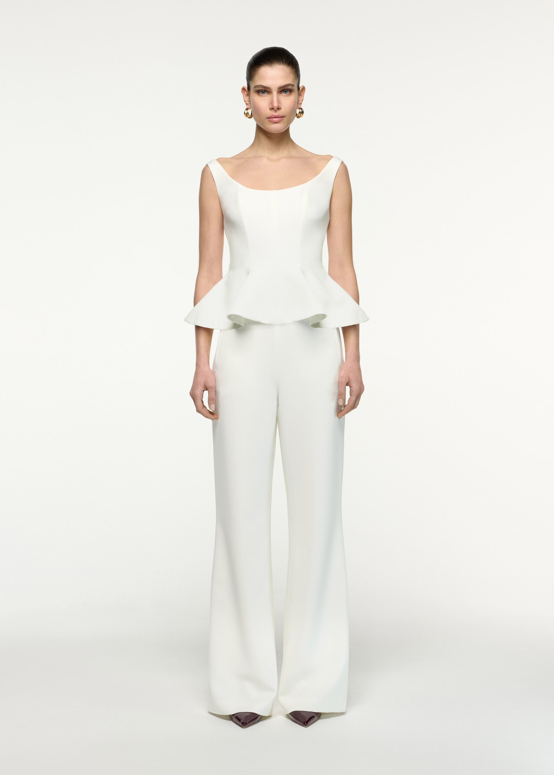 Front view of a model wearing the Crepe Peplum Top in Cream