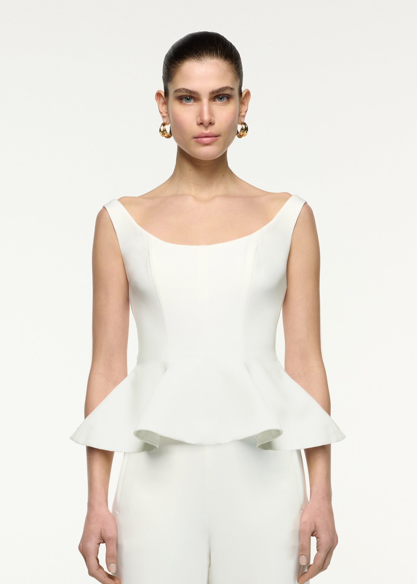Close up of a model wearing the Crepe Peplum Top in Cream