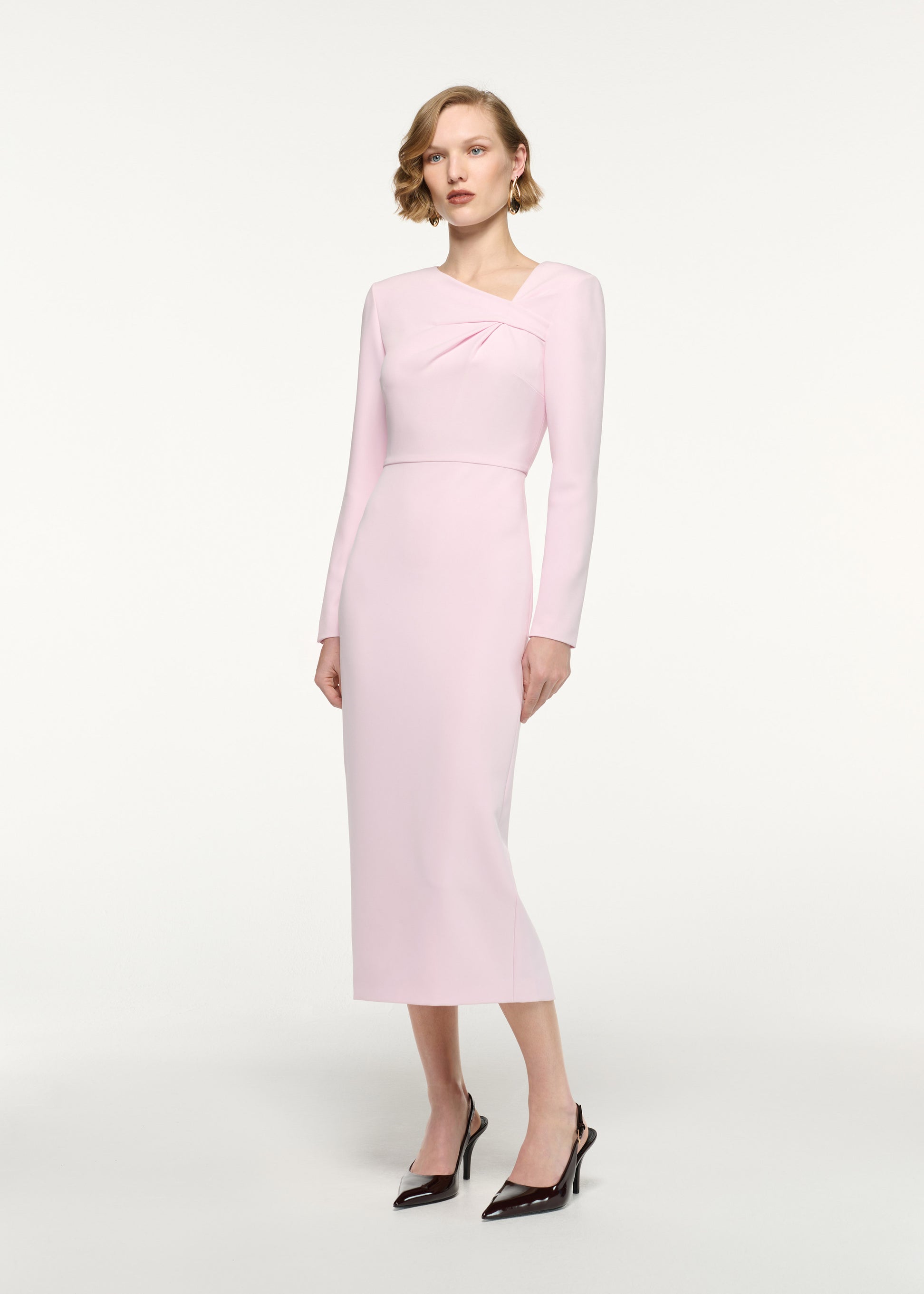 Side view of a model wearing the Asymmetric Twist Drape Midi Dress in Pink