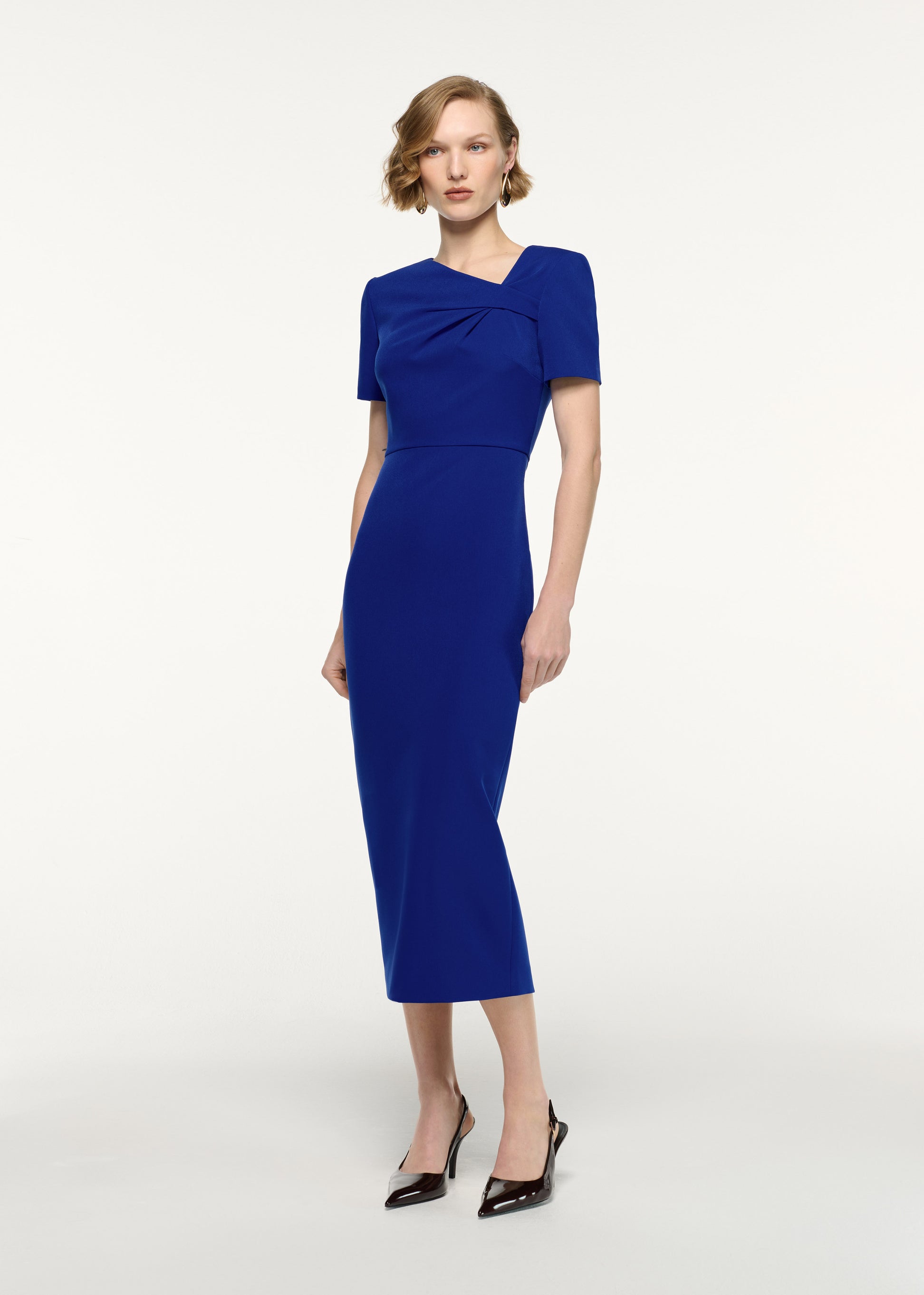 Side view of a model wearing the Asymmetric Twist Drape Midi Dress in Blue