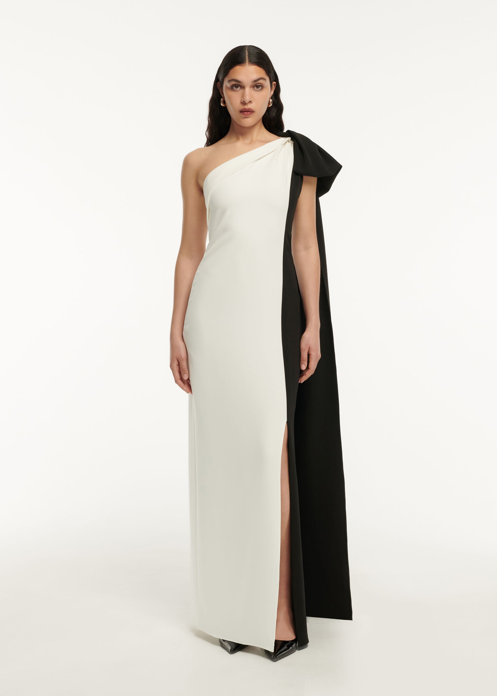 A woman wearing the Asymmetric Stretch Cady Bow Maxi Dress in Monochrome