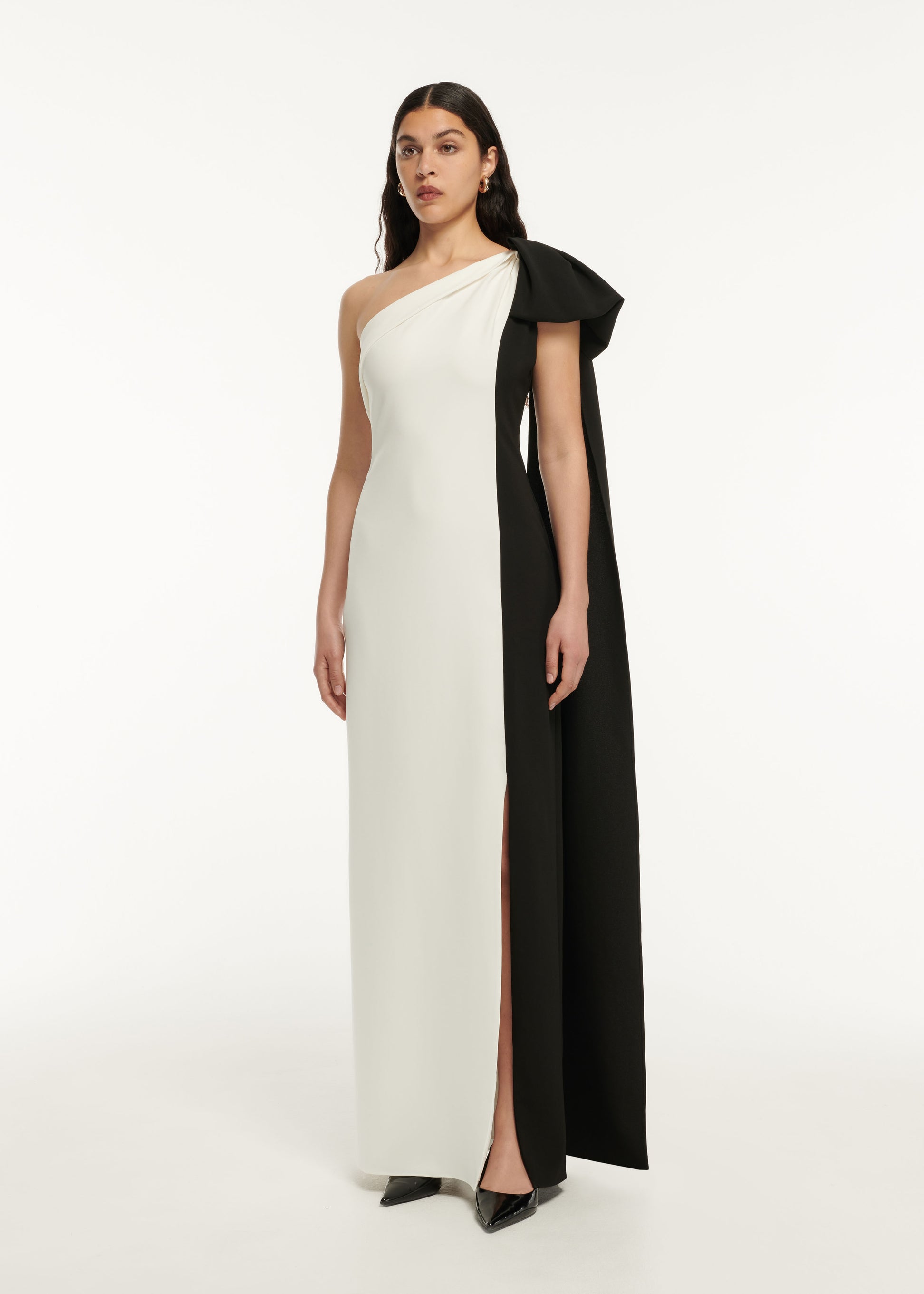 A woman wearing the Asymmetric Stretch Cady Bow Maxi Dress in Monochrome