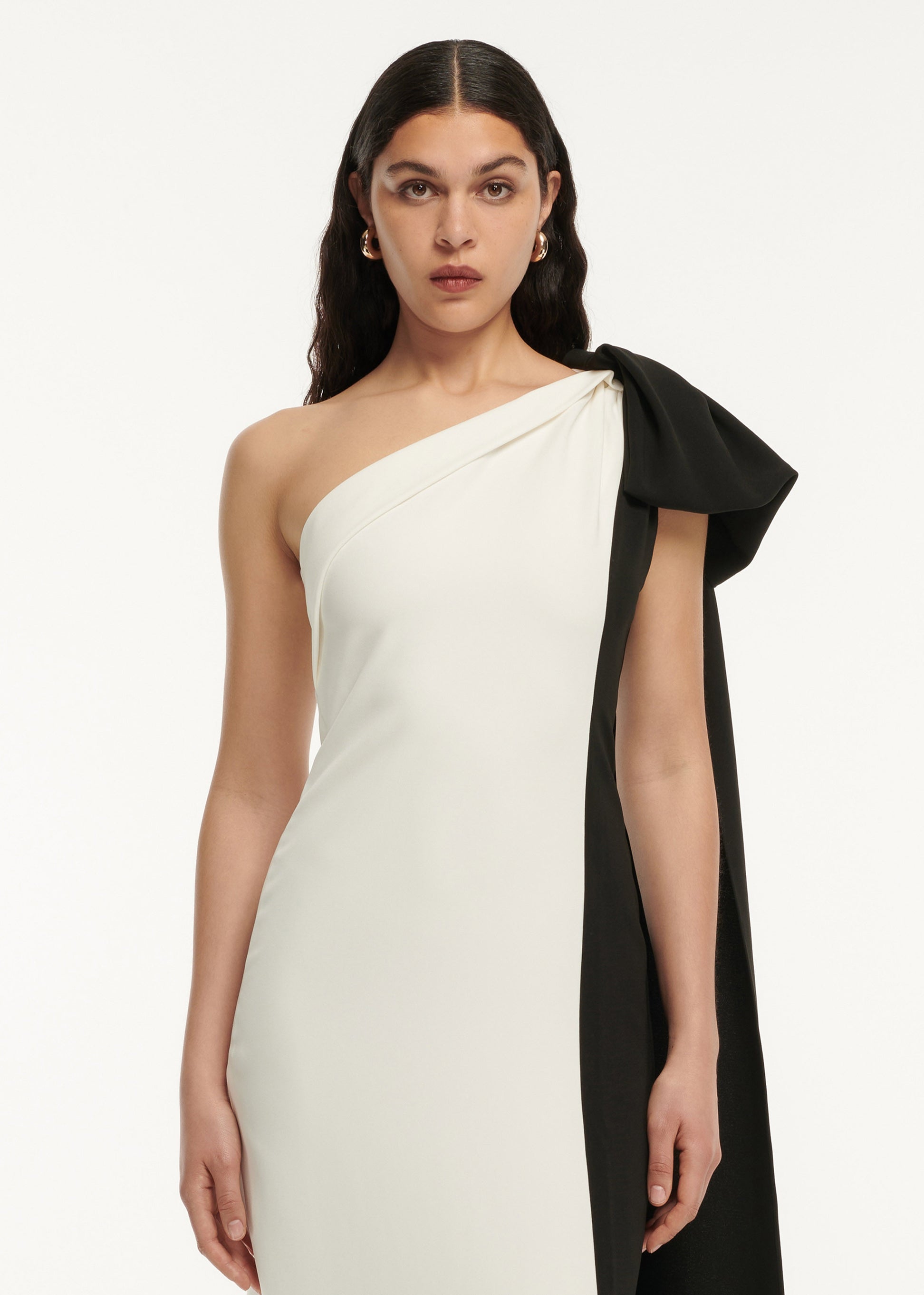 A close up of a woman wearing the Asymmetric Bow Stretch Cady Maxi Dress