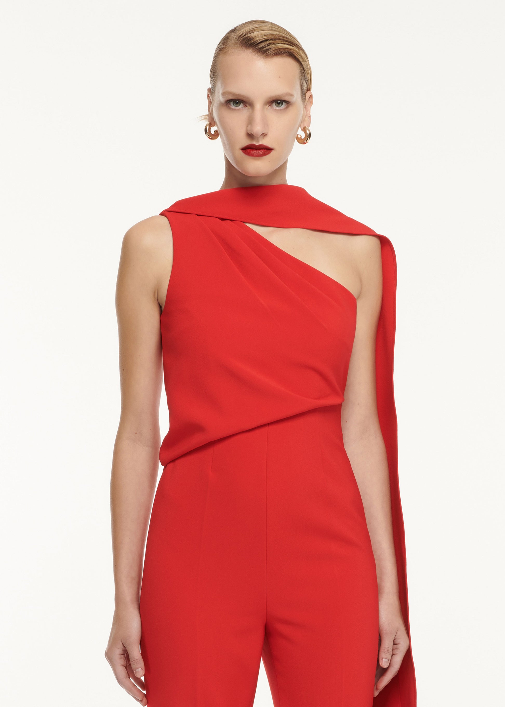 A close up of a woman wearing the Asymmetric Crepe Jumpsuit Red