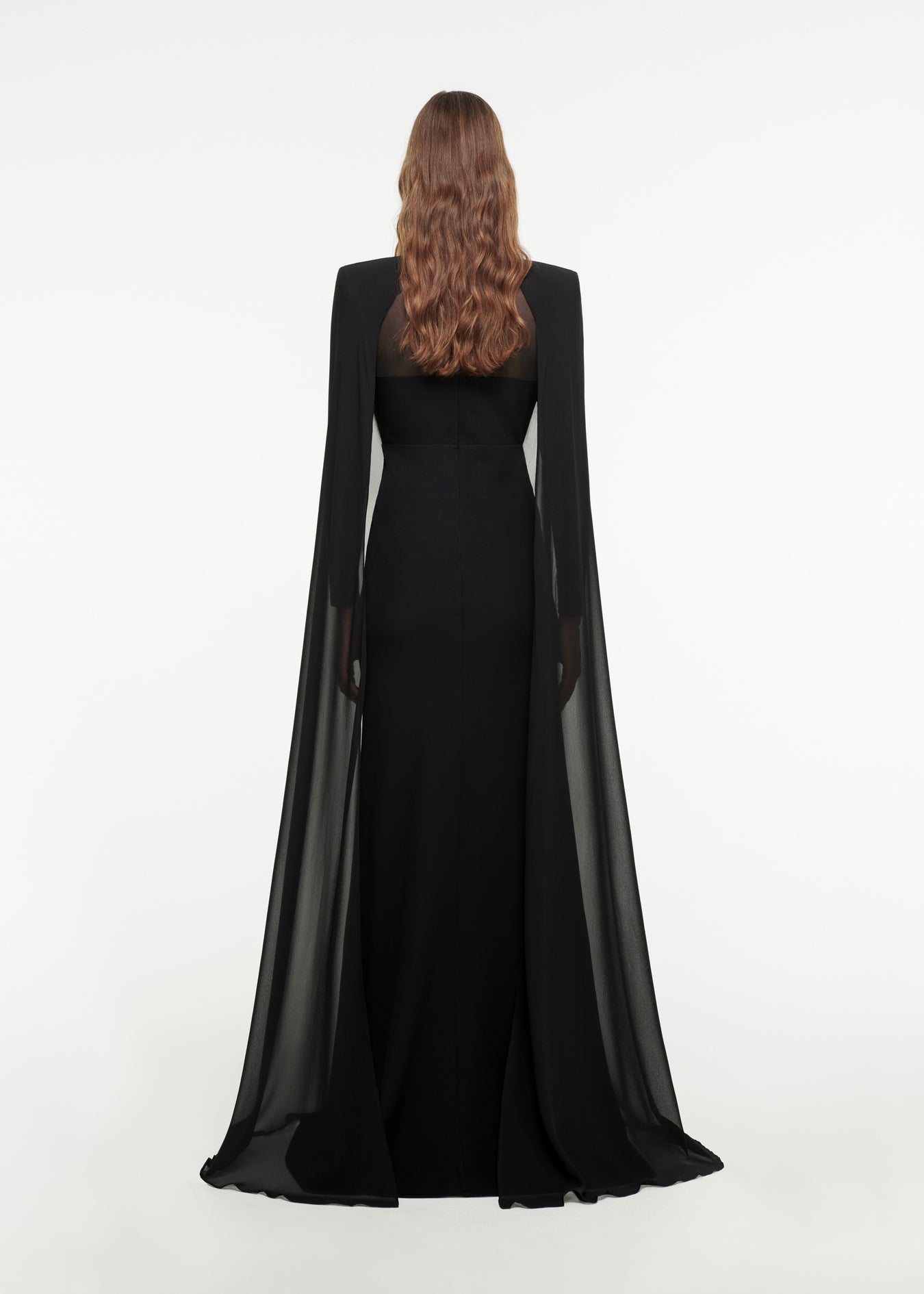 The back of a woman wearing the Long Sleeve Cape Gown in Black