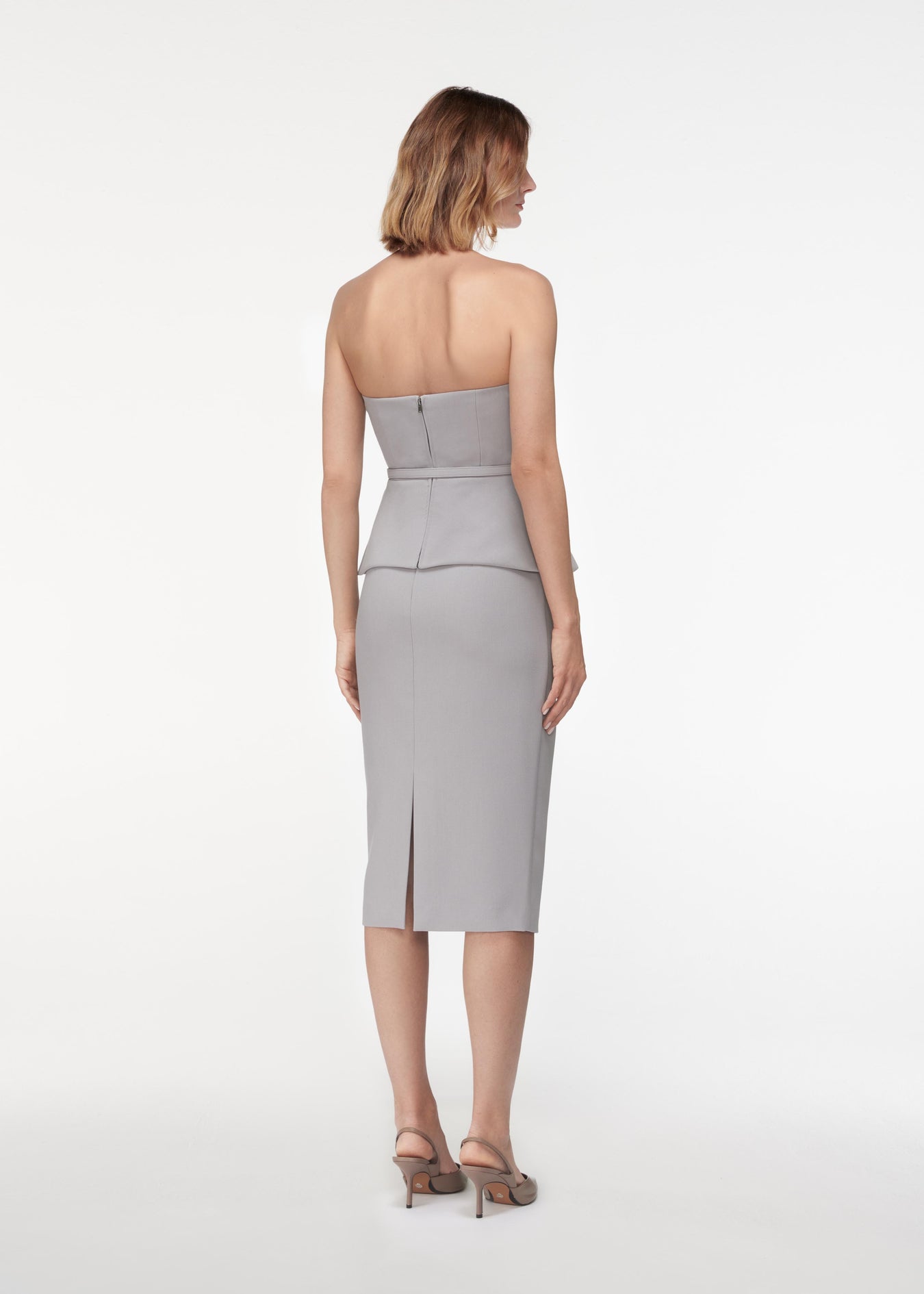 A photograph of a woman wearing a Strapless Crepe Peplum Top in Grey