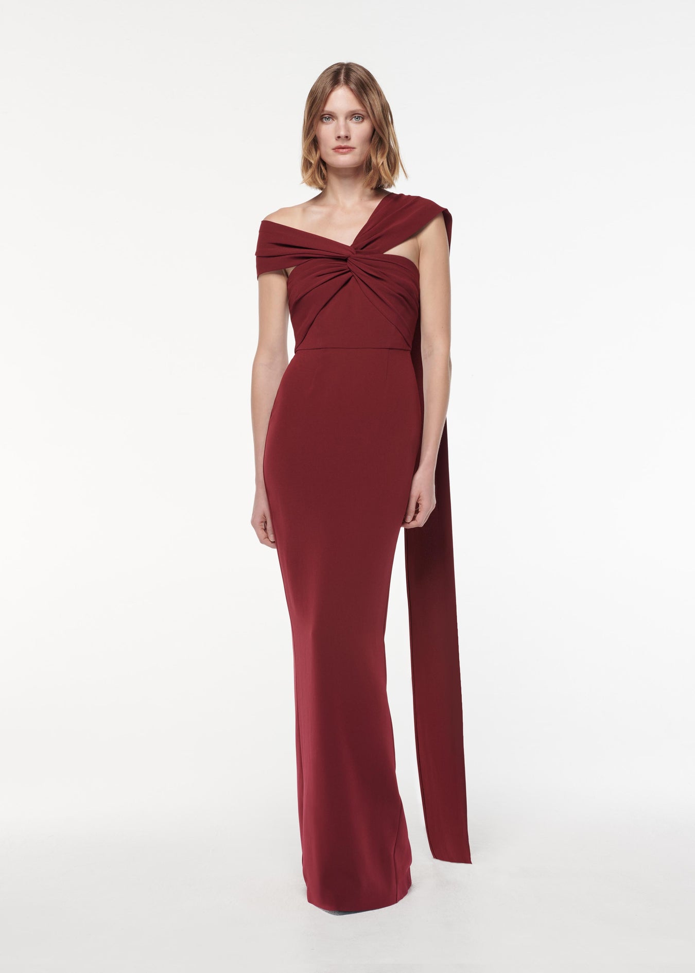 A photograph of a woman wearing aAsymmetric Light Cady Gown in Burgundy