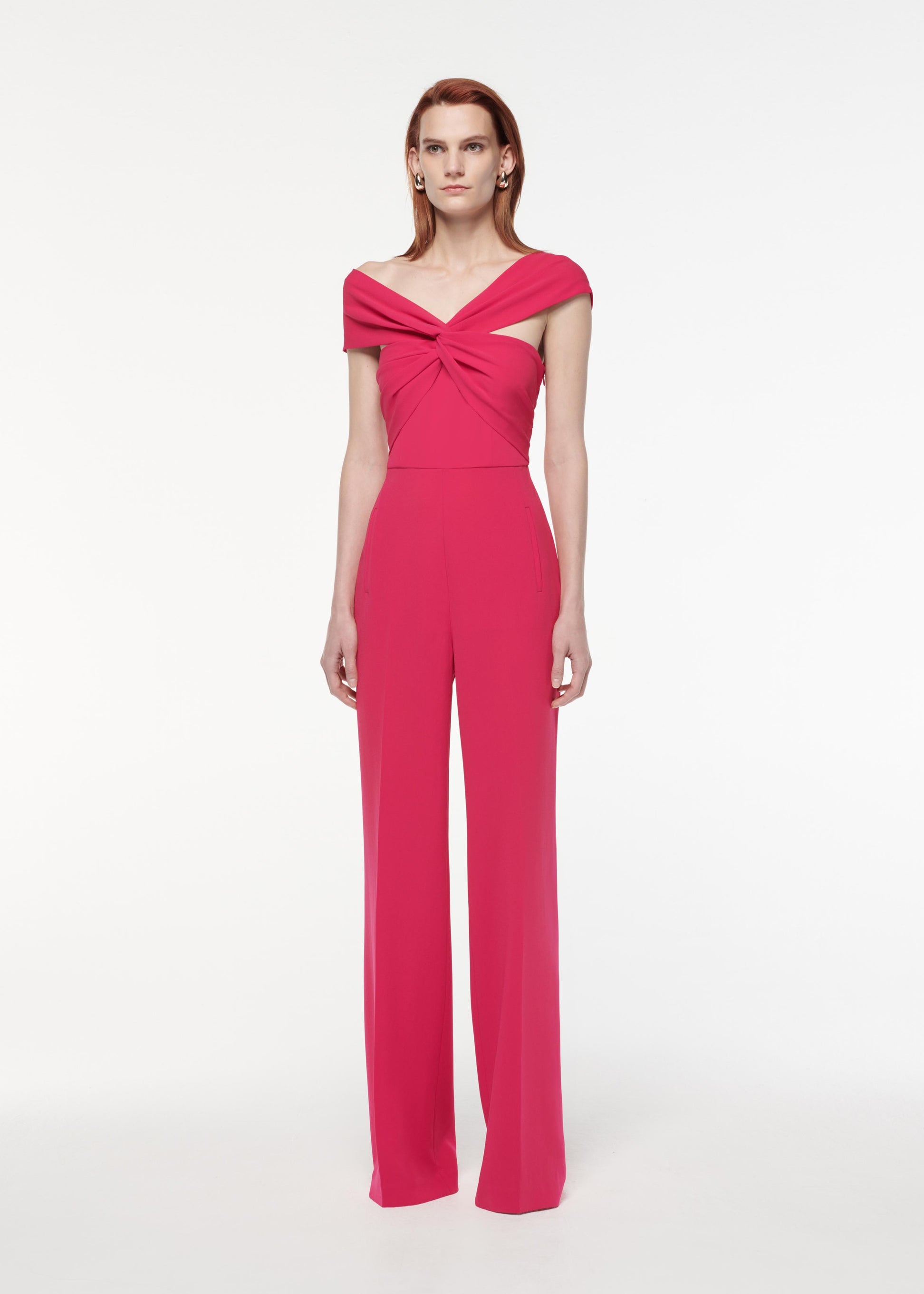 A photograph of a woman wearing a Asymmetric Light Cady Jumpsuit in Pink