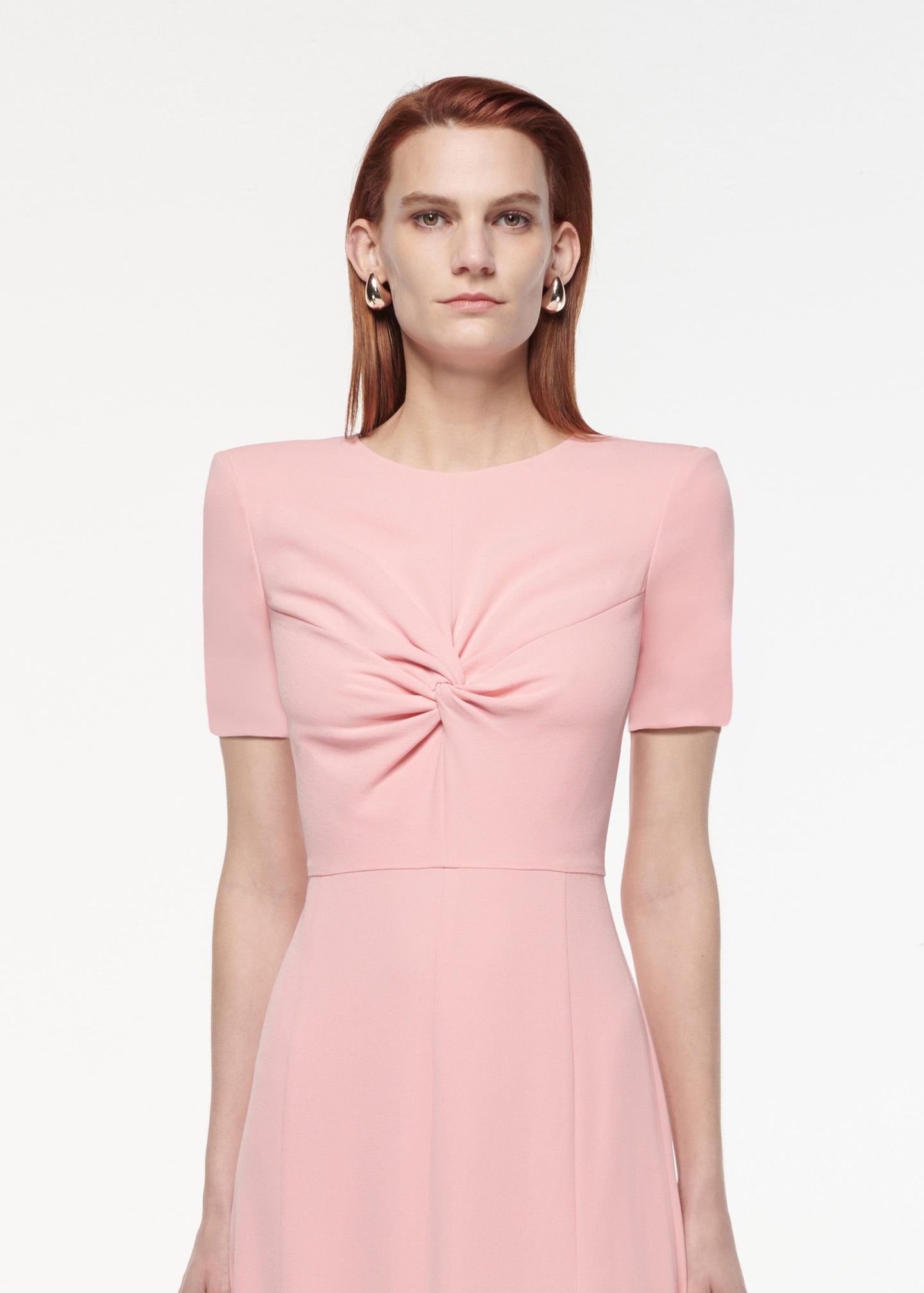 A photograph of a woman wearing a Short Sleeve Light Cady Midi Dress in Pink
