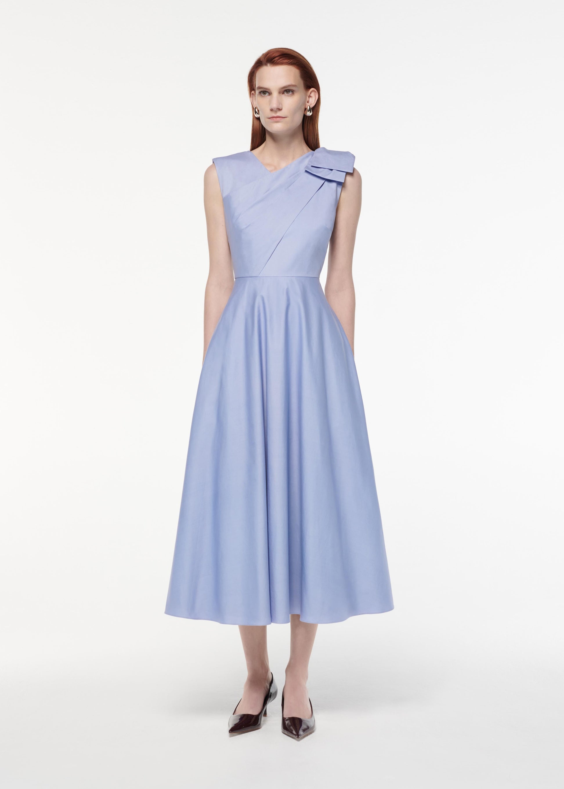 A photograph of a woman wearing a Bow Cotton Poplin Midi Dress in Blue