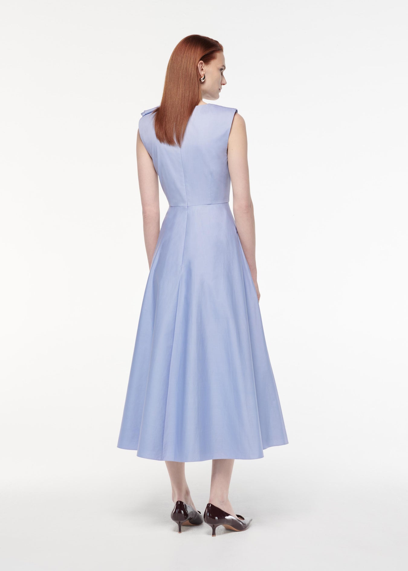 A photograph of a woman wearing a Bow Cotton Poplin Midi Dress in Blue