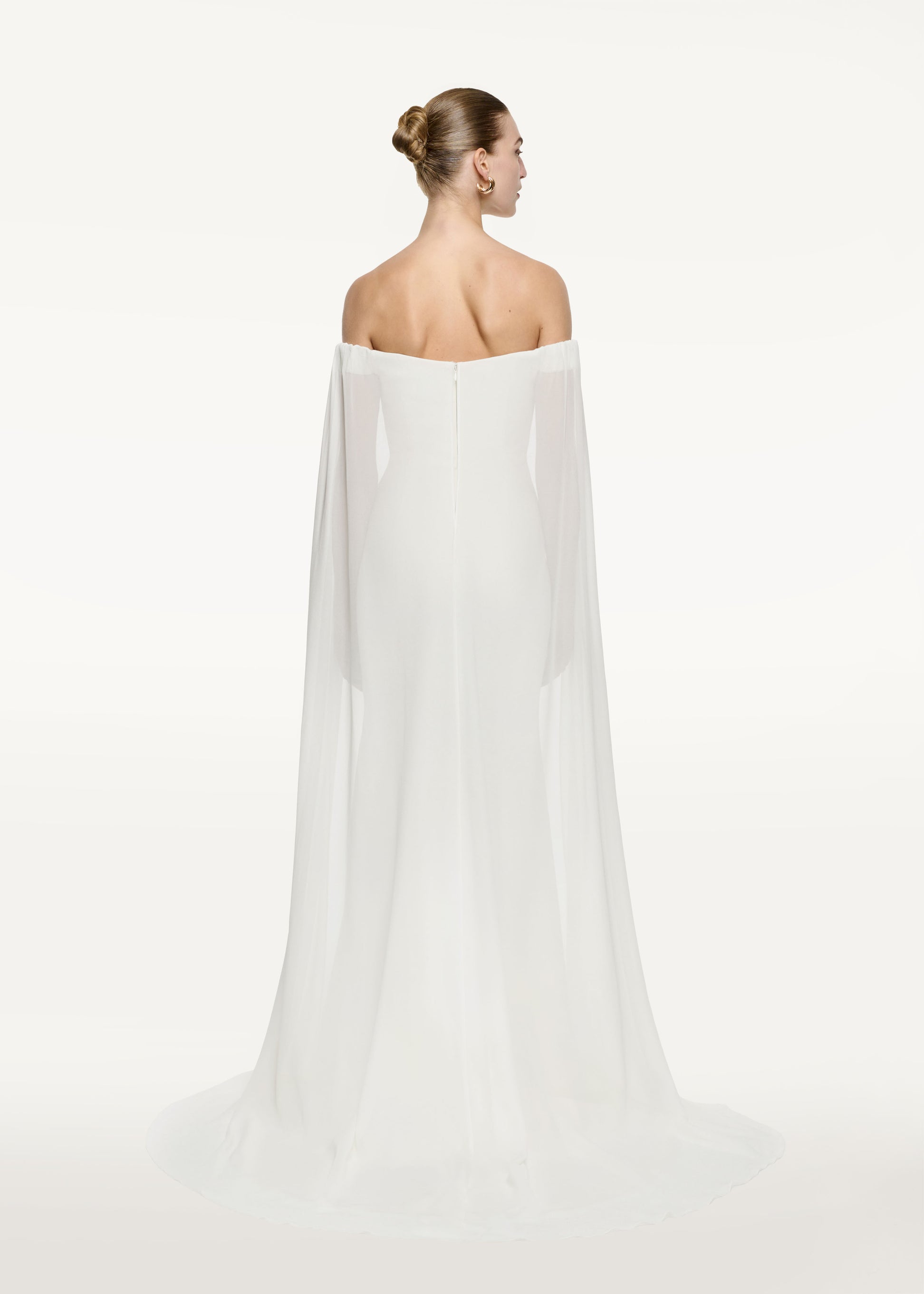 The back of a woman wearing the Off The Shoulder Stretch Cady Gown in White