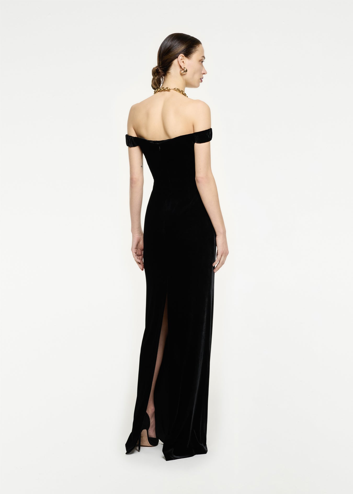 The back of a woman wearing the Off The Shoulder Velvet Maxi Dress in Black