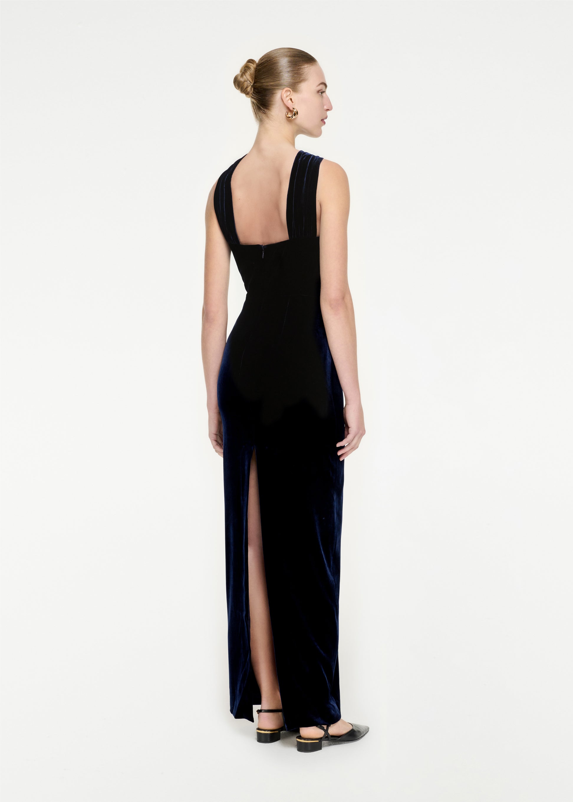 The back of a woman wearing the Asymmetric Velvet Maxi Dress in Navy