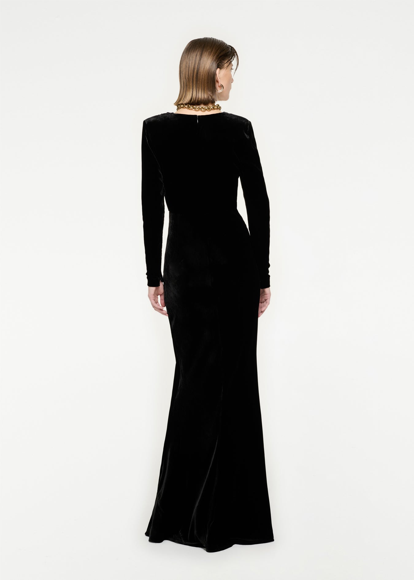 The back of a woman wearing the Long Sleeve Velvet Maxi Dress in Black