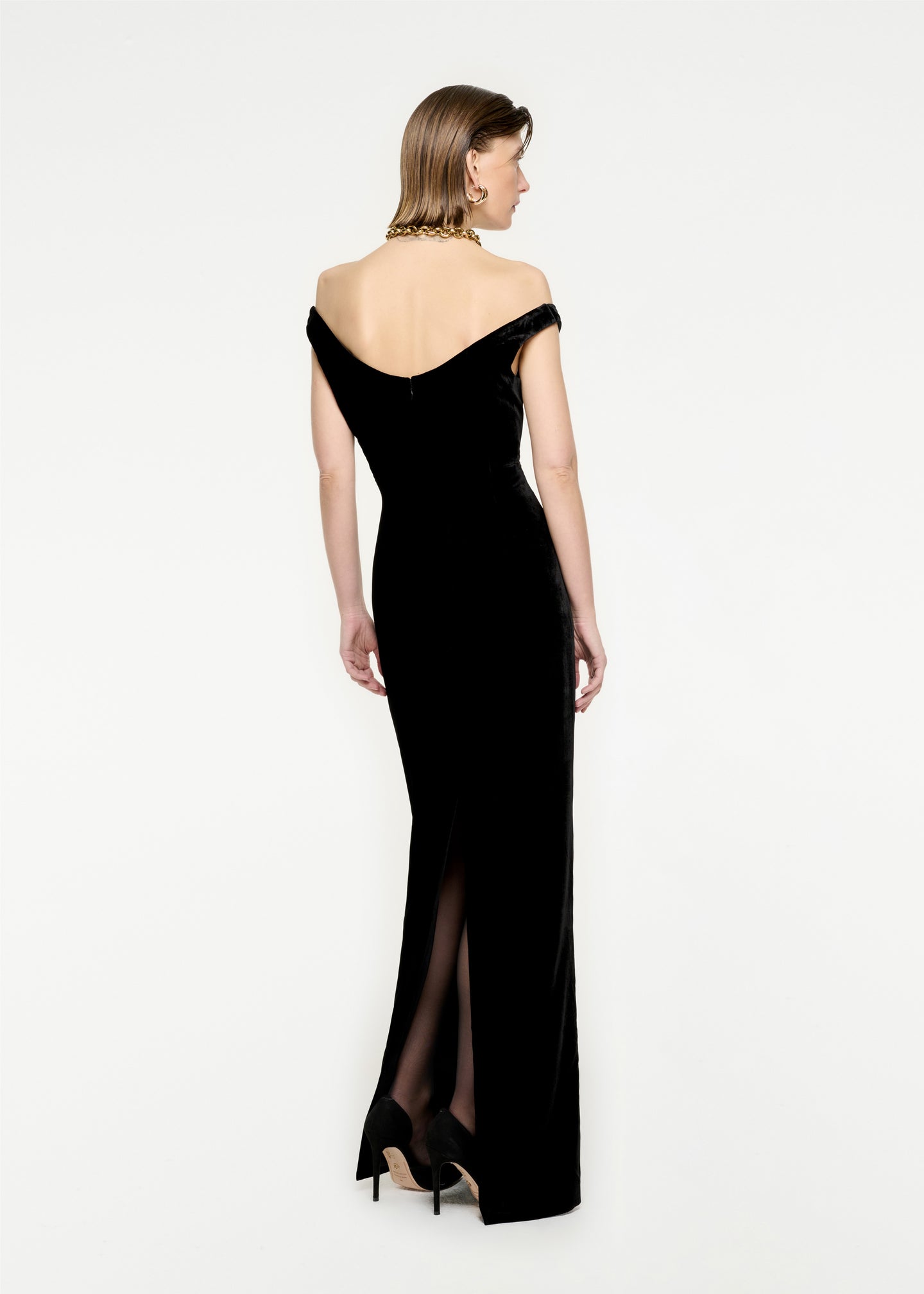 The back of a woman wearing the Off The Shoulder Velvet Maxi Dress in Black