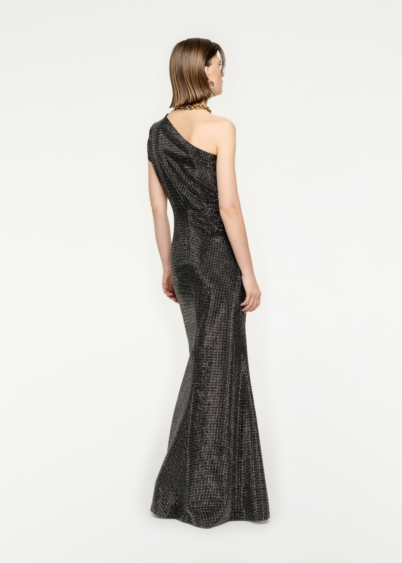 The back of a woman wearing the Asymmetric Diamante Maxi Dress in Black