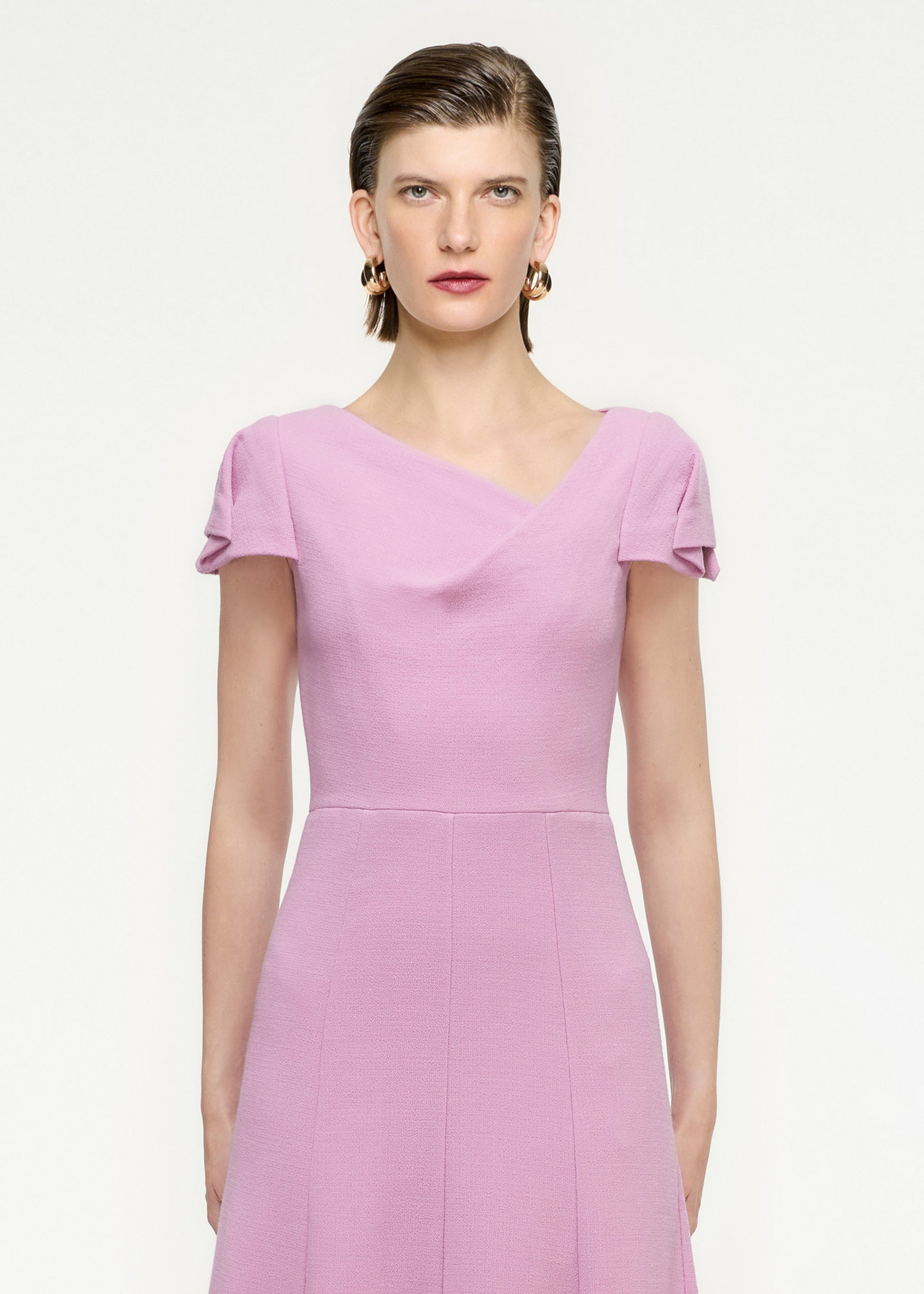 A close up of a woman wearing the Cap Sleeve Wool Crepe Midi Dress in Pink