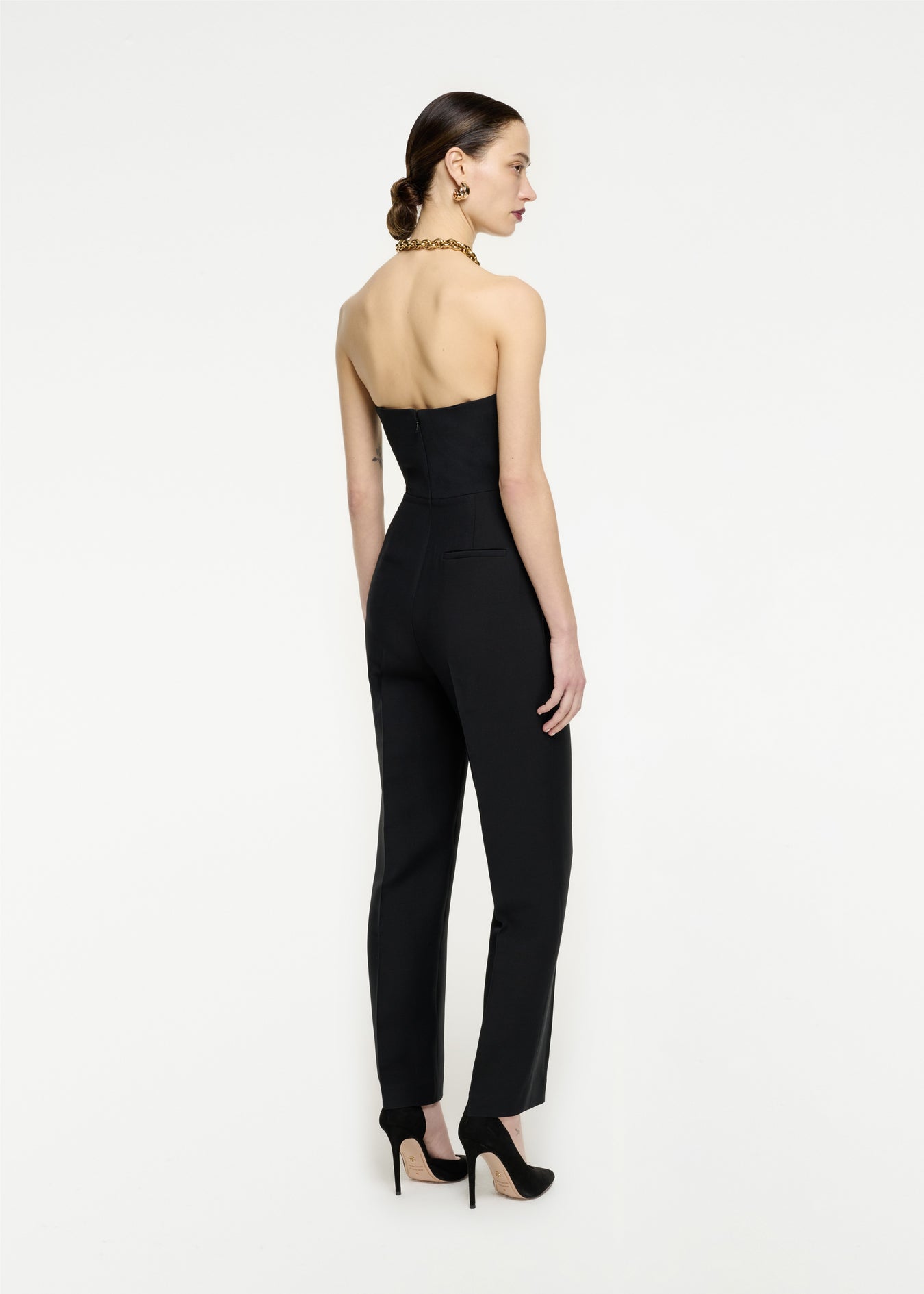 The back of a woman wearing the Strapless Wool Silk Jumpsuit in Black