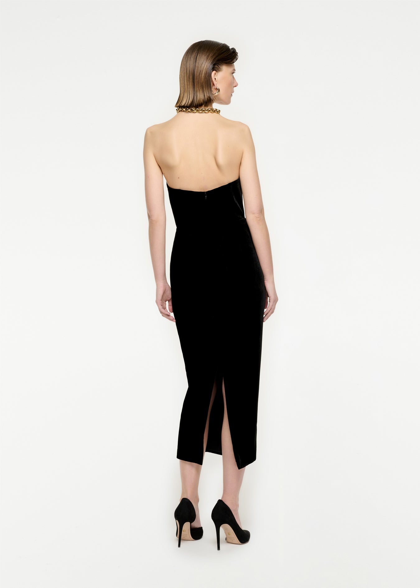 The back of a woman wearing the Strapless Velvet Midi Dress in Black