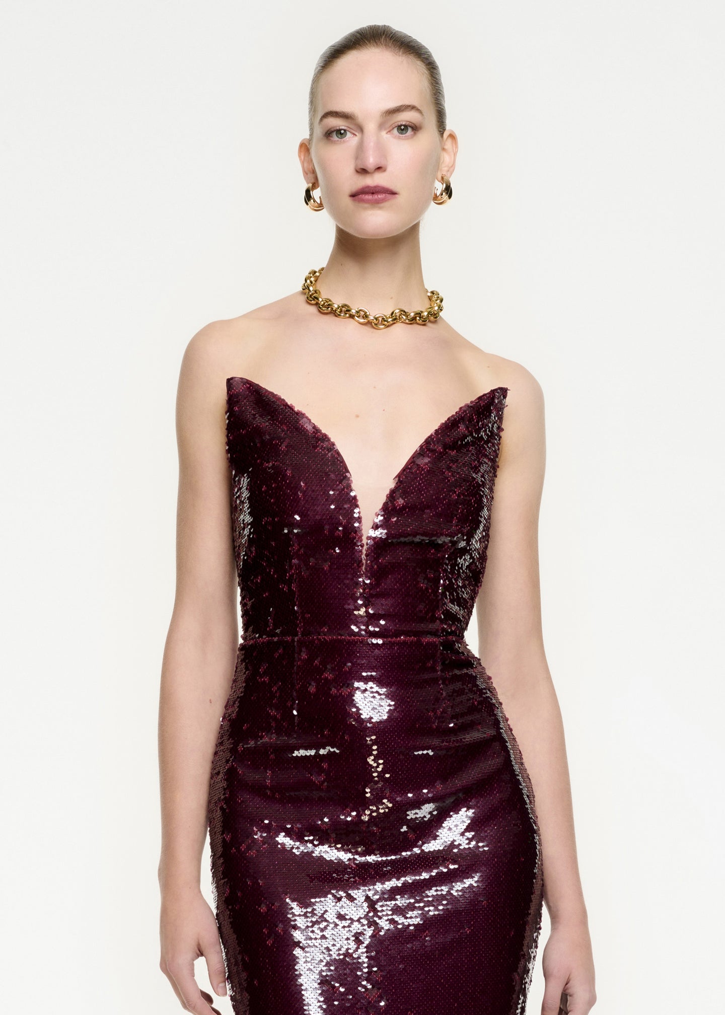 A close up of a woman wearing the Strapless Sequin Midi Dress in Maroon