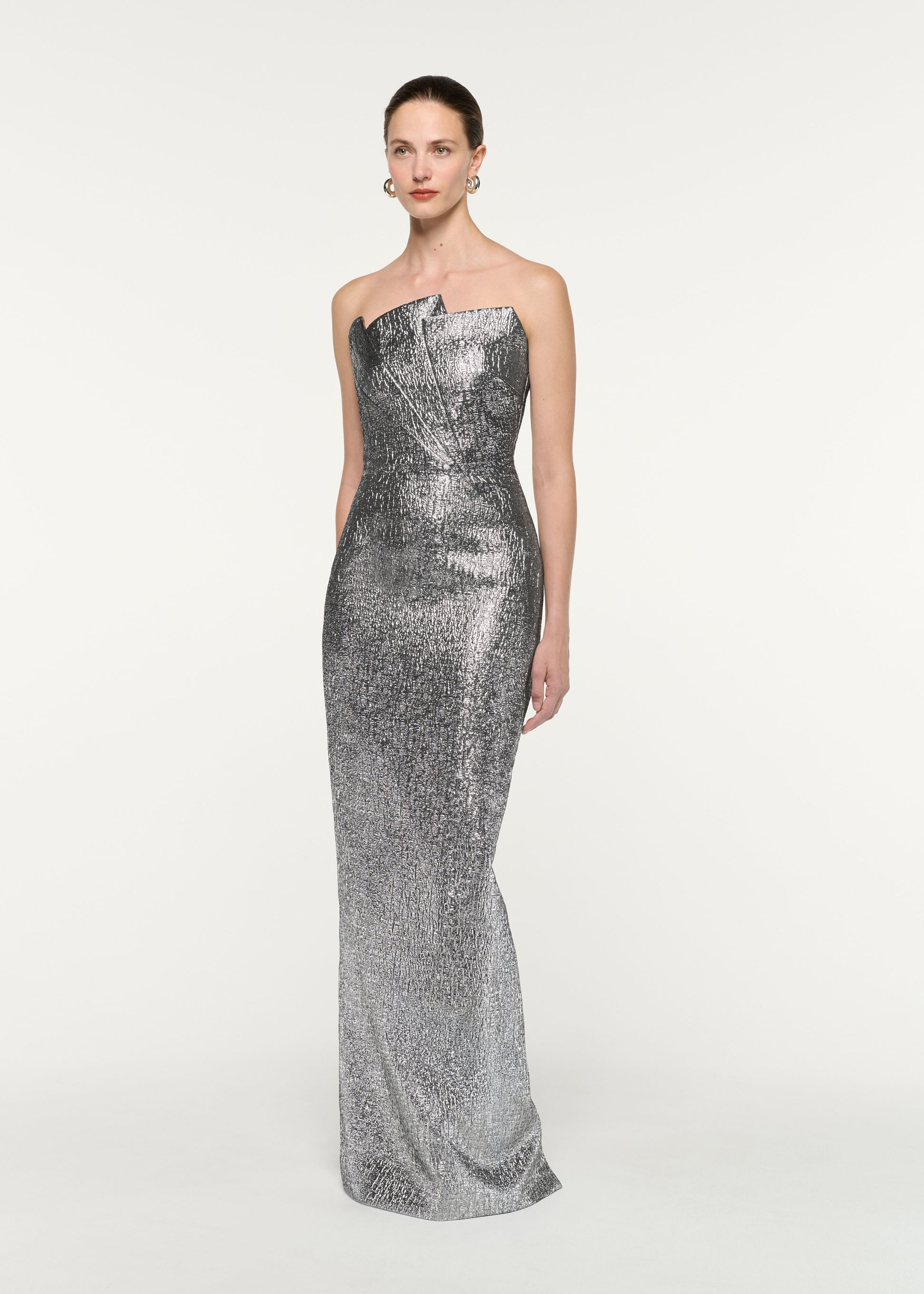 Side view of a model wearing the Pleated Strapless Metallic Jacquard Gown