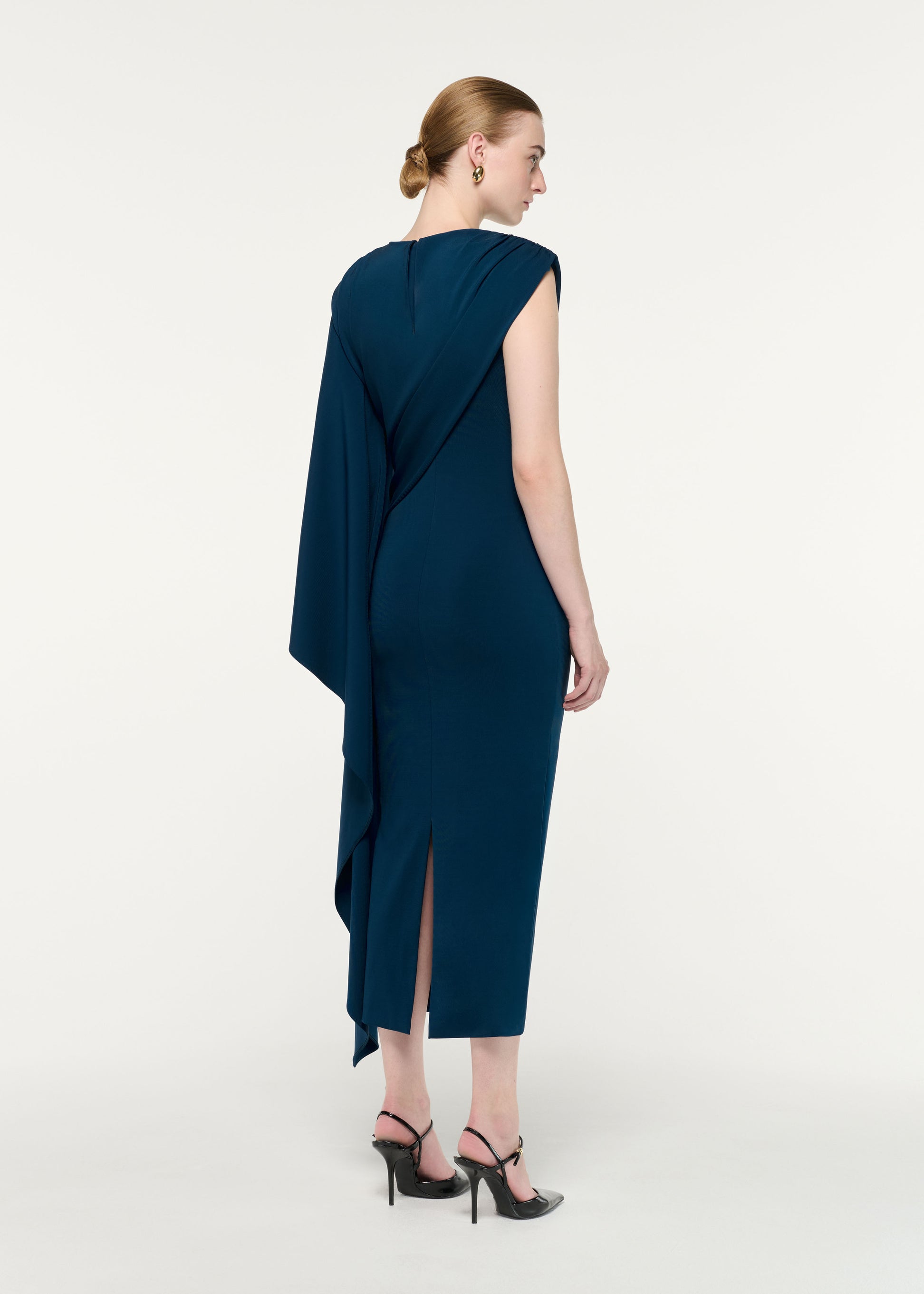 Back view of a model wearing the Asymmetric Cape Jersey Midi Dress