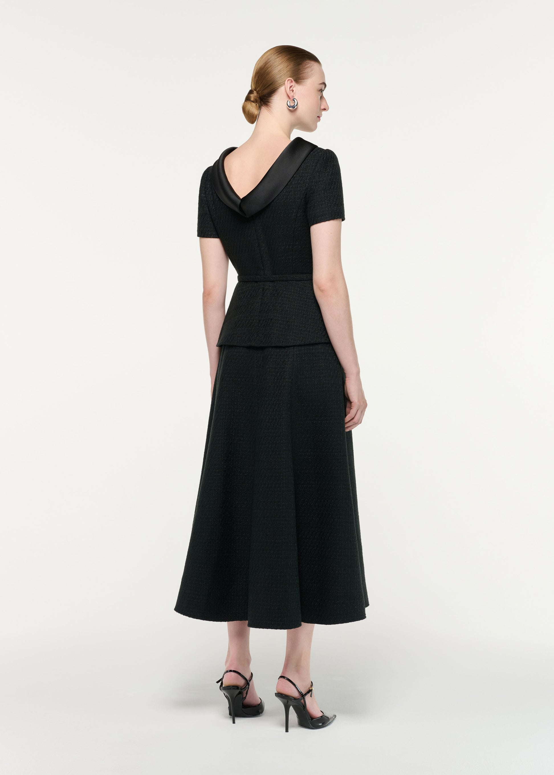 Back view of a model wearing the Collared Boucle Peplum Midi Dress