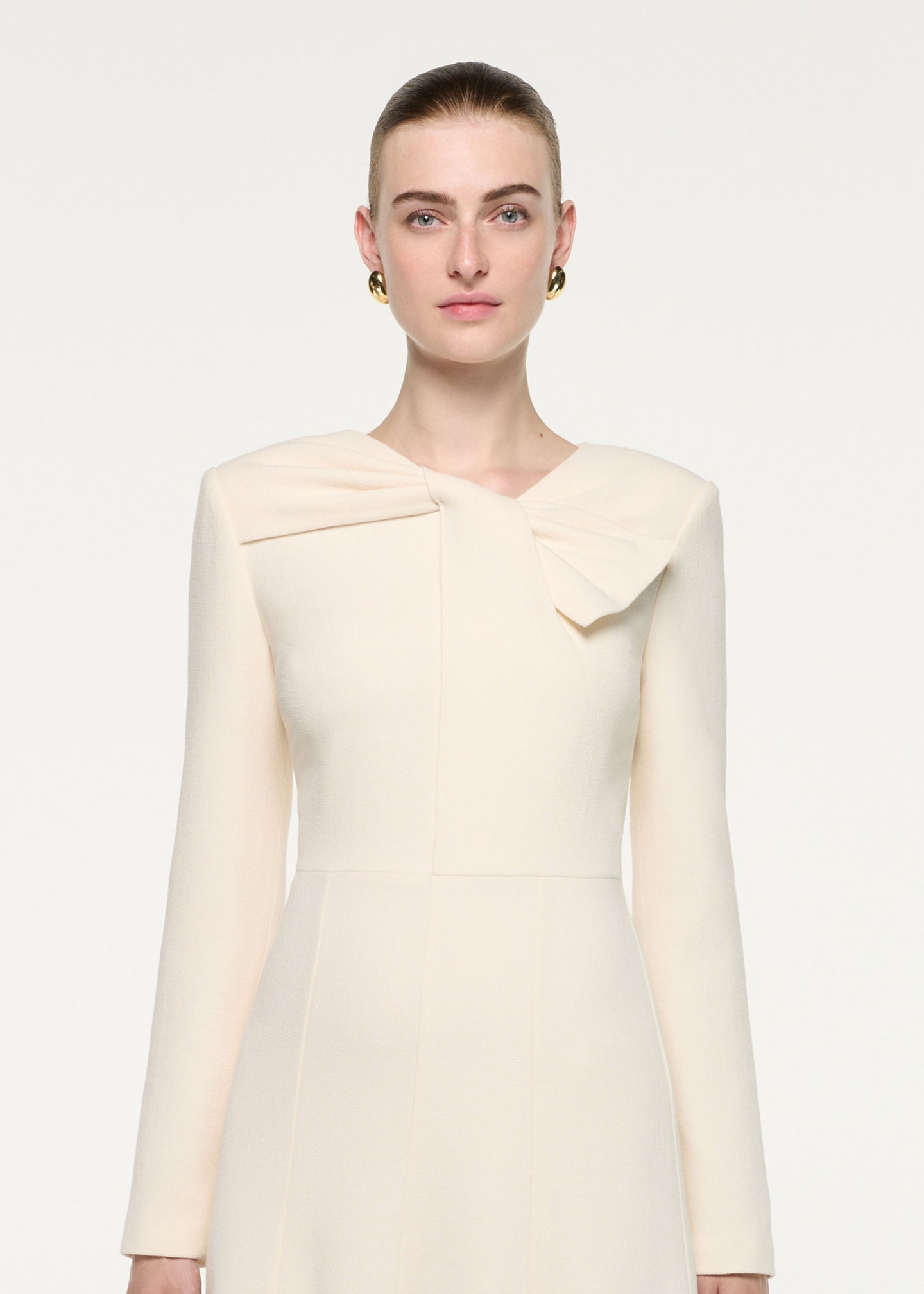 Close up of a model wearing the Asymmetric Bow Neck Wool Crepe Midi Dress