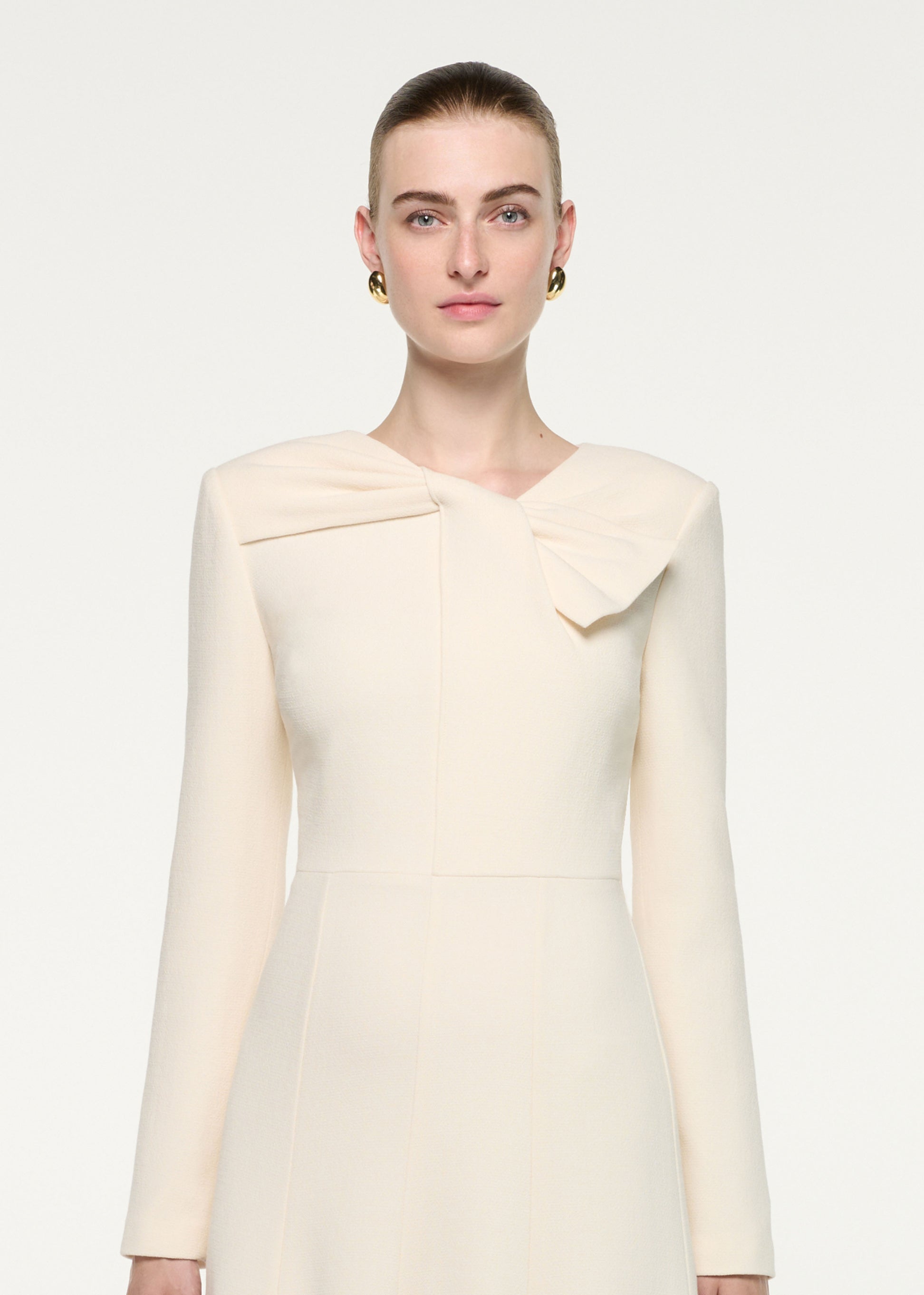 Close up of a model wearing the Asymmetric Bow Neck Wool Crepe Midi Dress