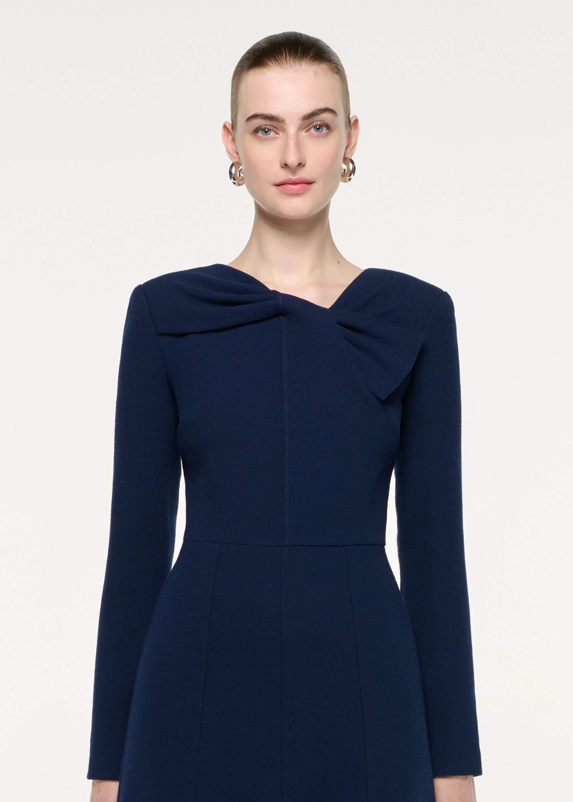 Close up of a model wearing the Asymmetric Bow Neck Wool Crepe Midi Dress