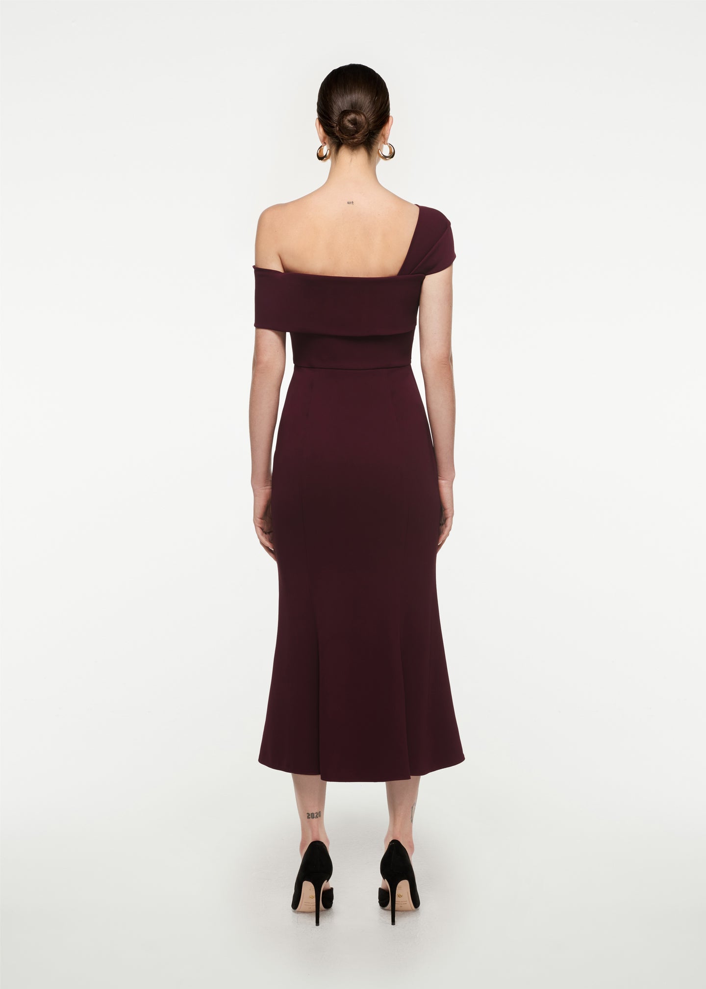 The back of a woman wearing the Asymmetric Stretch Cady Midi Dress in Maroon