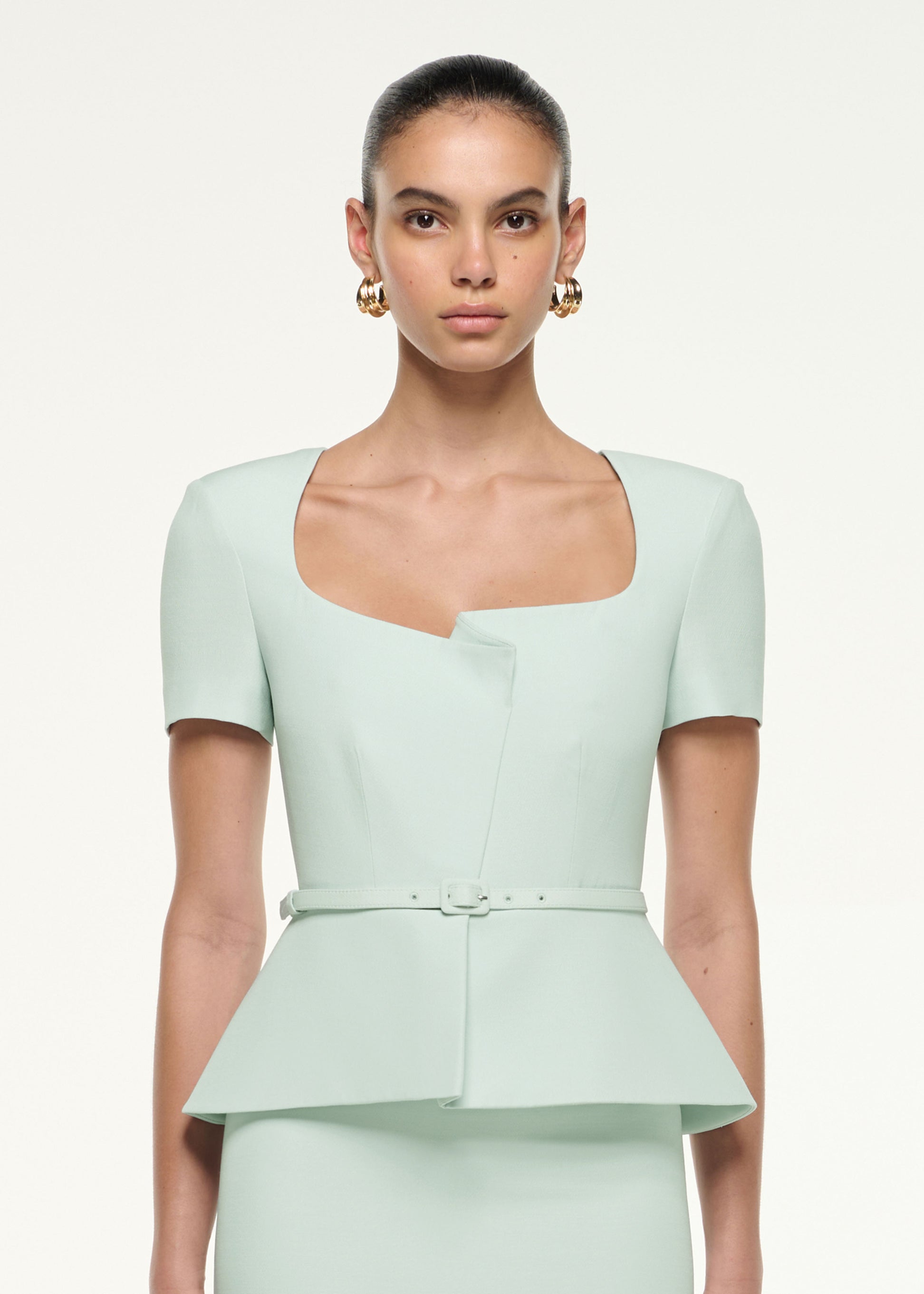 Close up of a model wearing the Peplum Wool Silk Midi Dress in Mint
