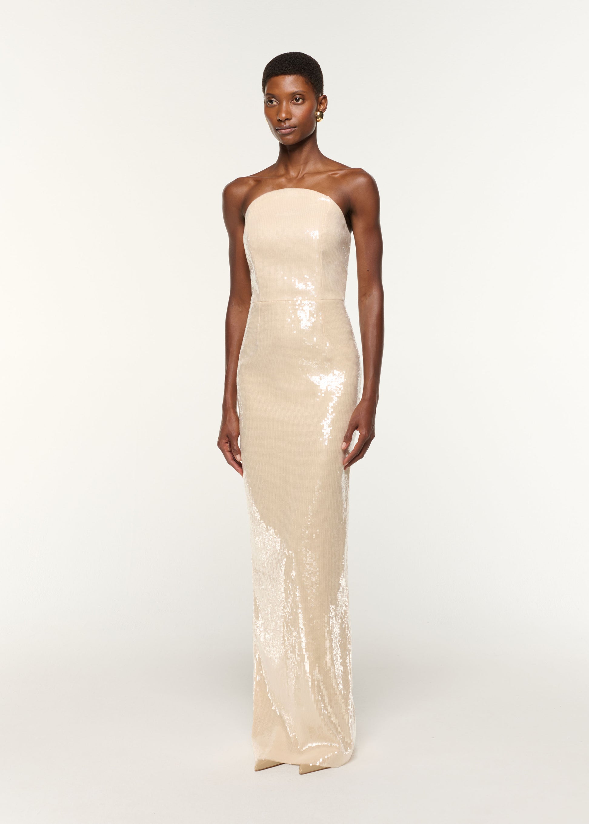 Side view of a model wearing the Curved Neckline Sequin Column Gown in Cream