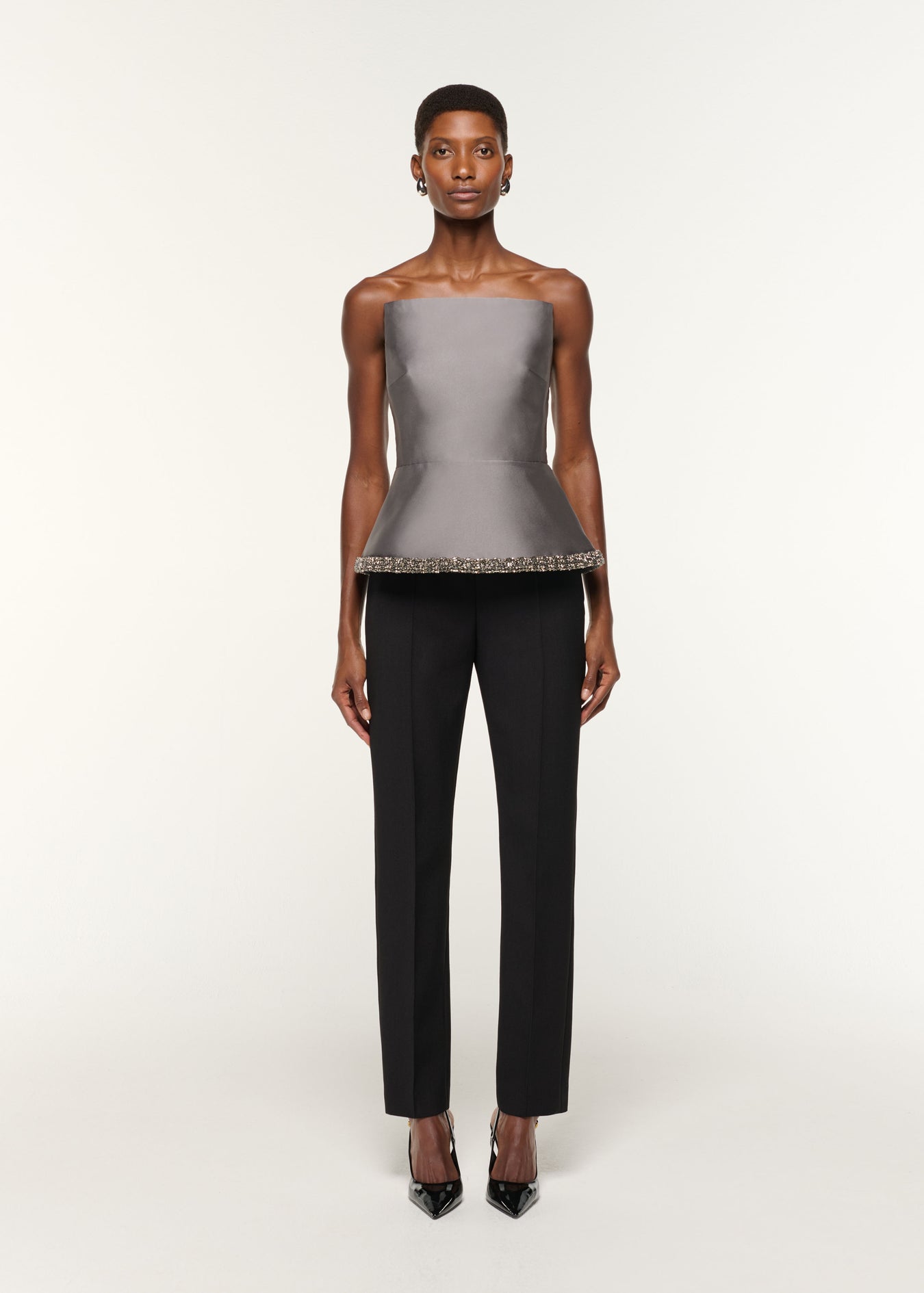 Front view of a model wearing the Square Neck With Crystal Trim Peplum Taffeta Top in Grey