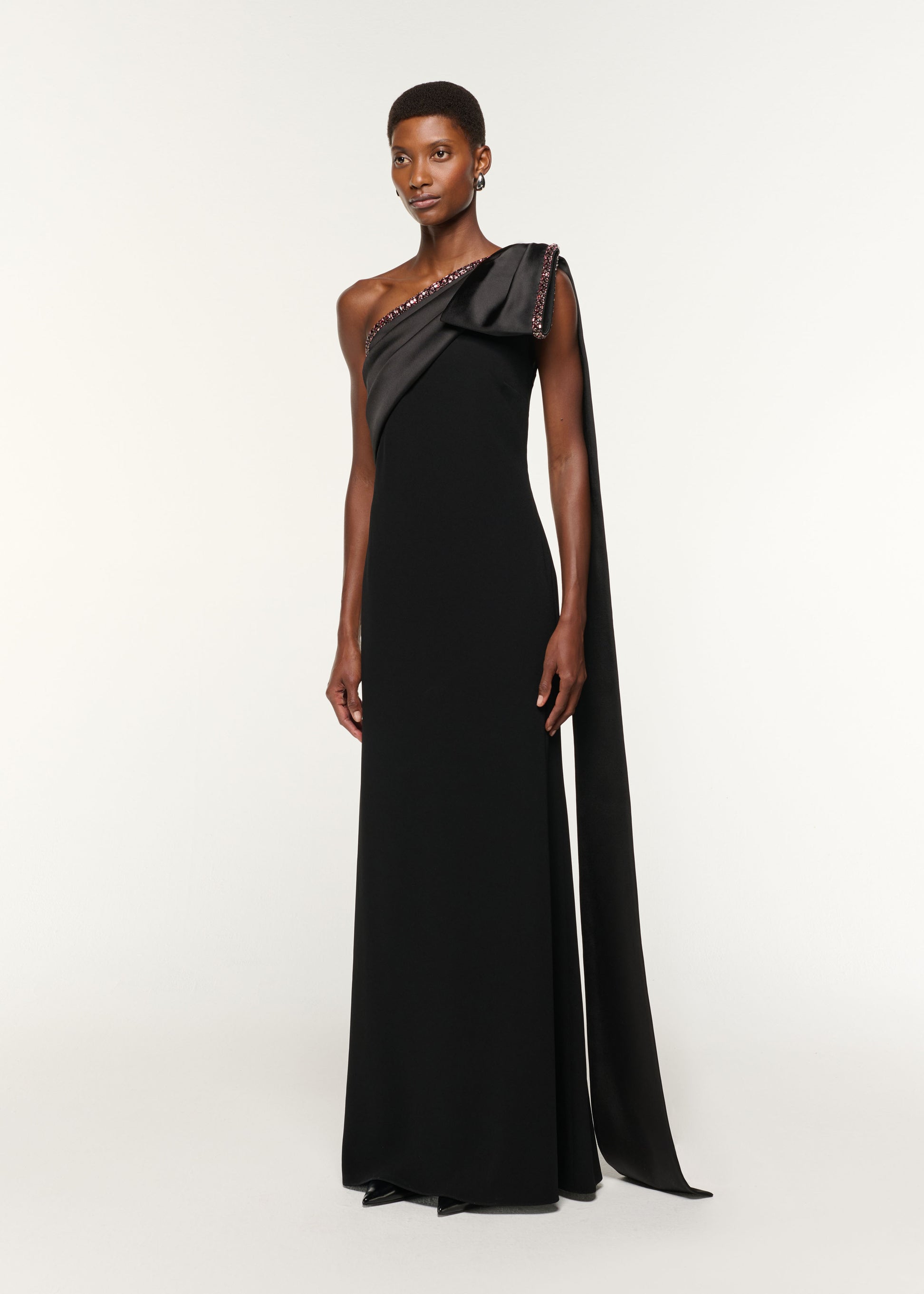 Side view of a model wearing the Contrast Crystal Trimmed Bow Satin Crepe Gown in Black