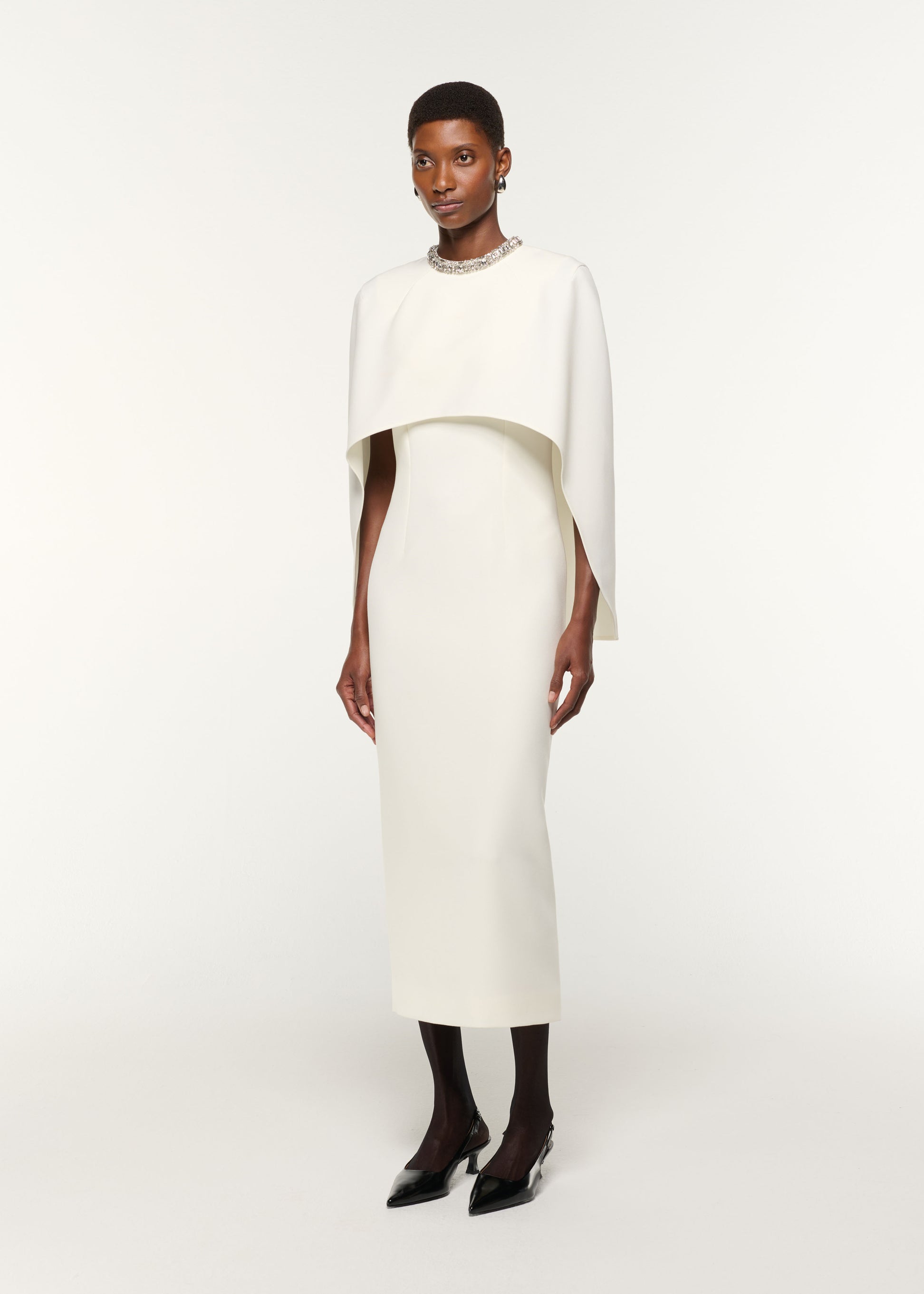 Side view of a model wearing the Crystal Neckline Crepe Cape Dress in Cream