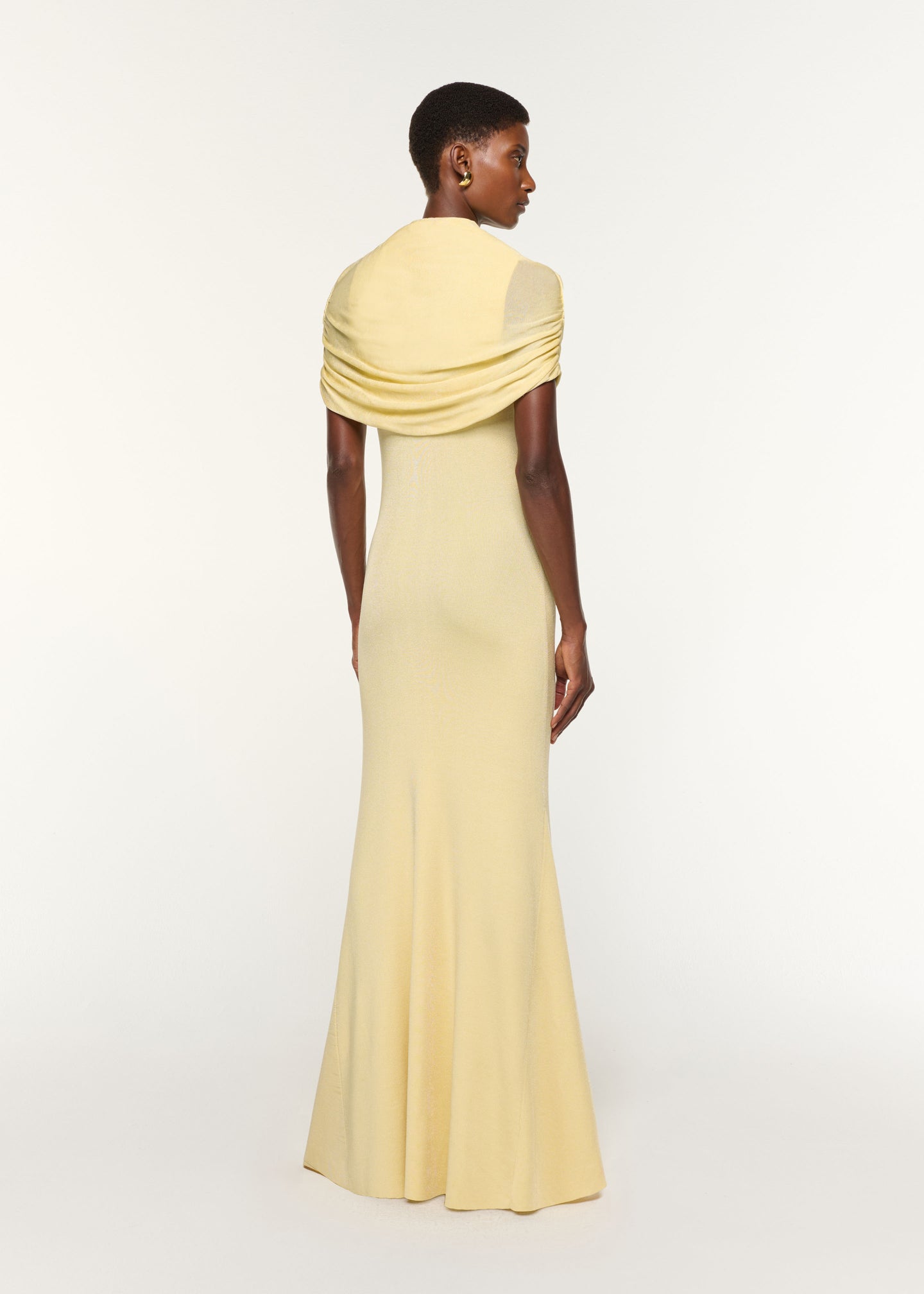 Back view of a model wearing the Draped Shawl Viscose Knit Dress in Yellow