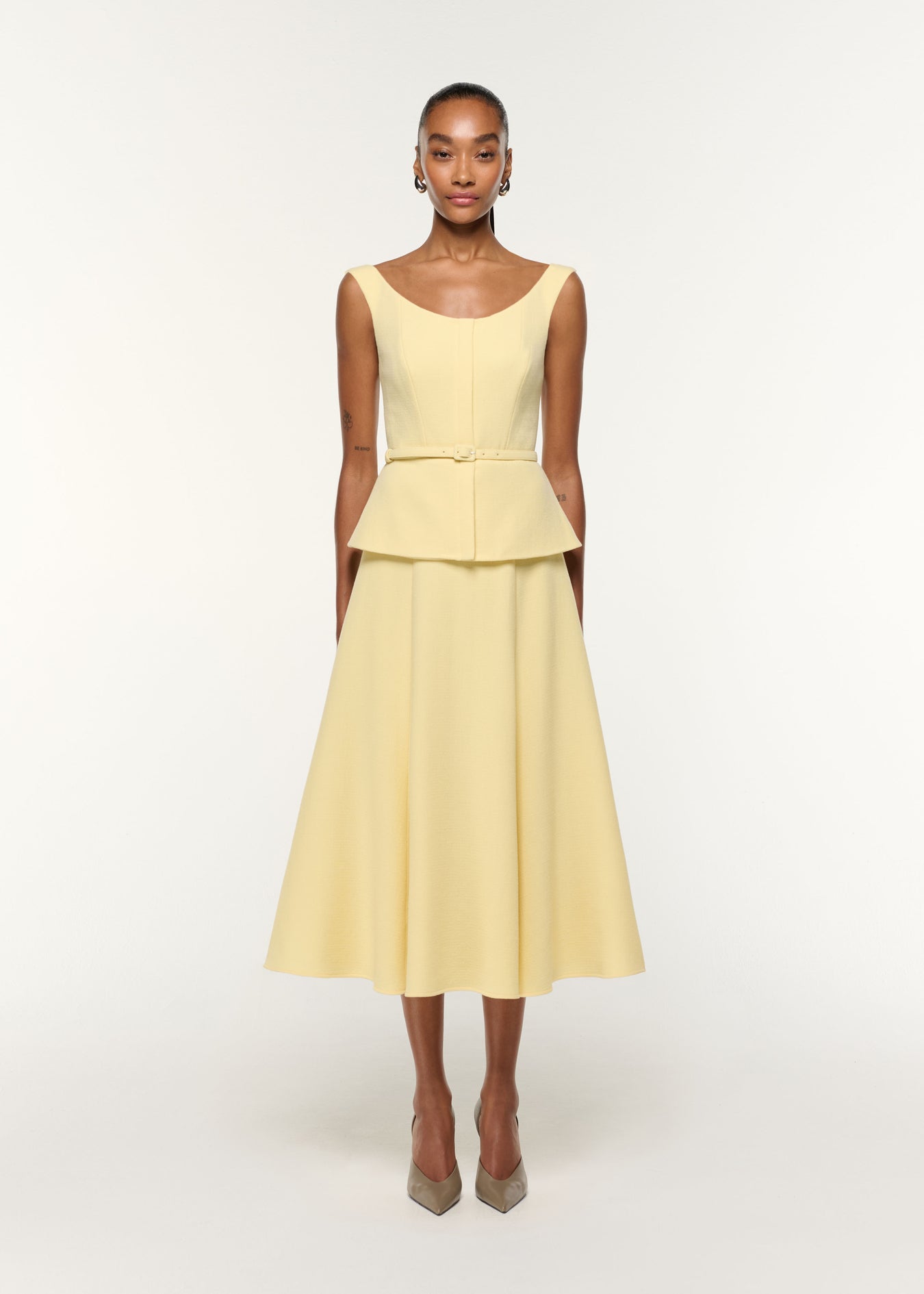Front view of a model wearing the Structured Peplum Wool Crepe Dress in Yellow