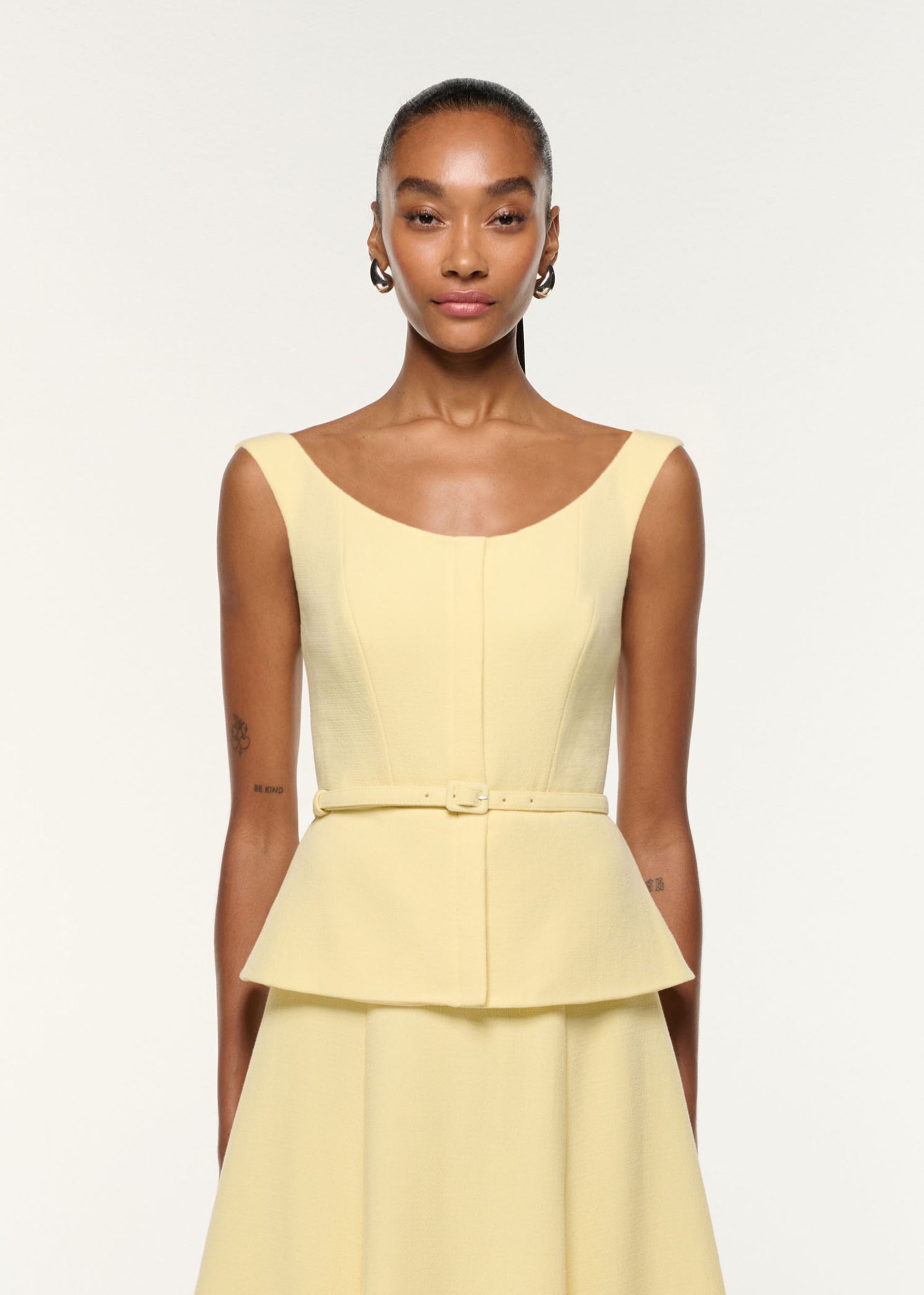 Close up of a model wearing the Structured Peplum Wool Crepe Dress in Yellow