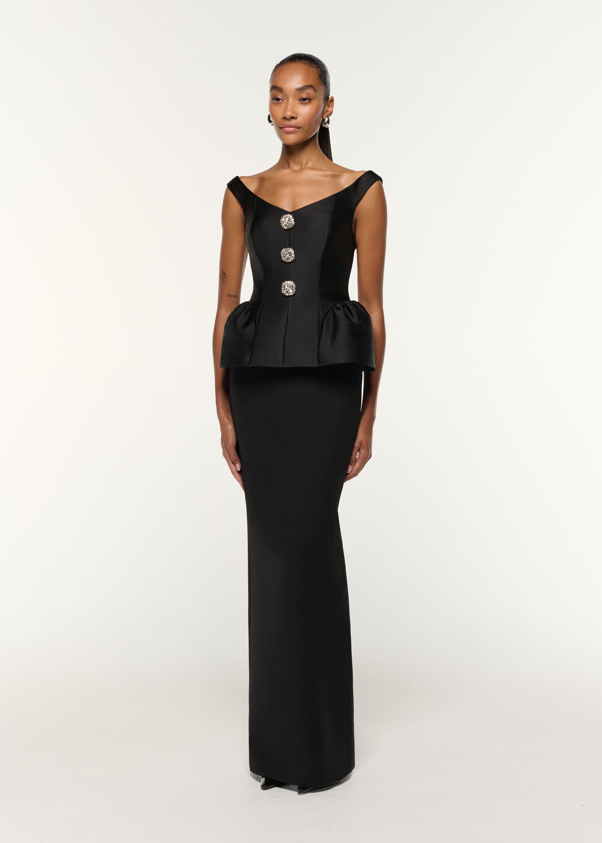 Side view of a model wearing the Crystal Button Peplum Taffeta Crepe Gown in Black
