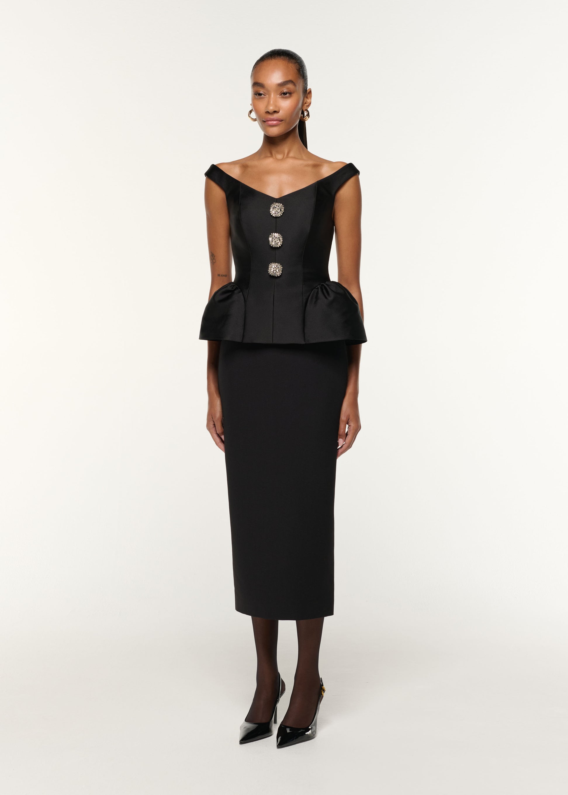 Side view of a model wearing the Crystal Button Peplum Taffeta Crepe Dress in Black
