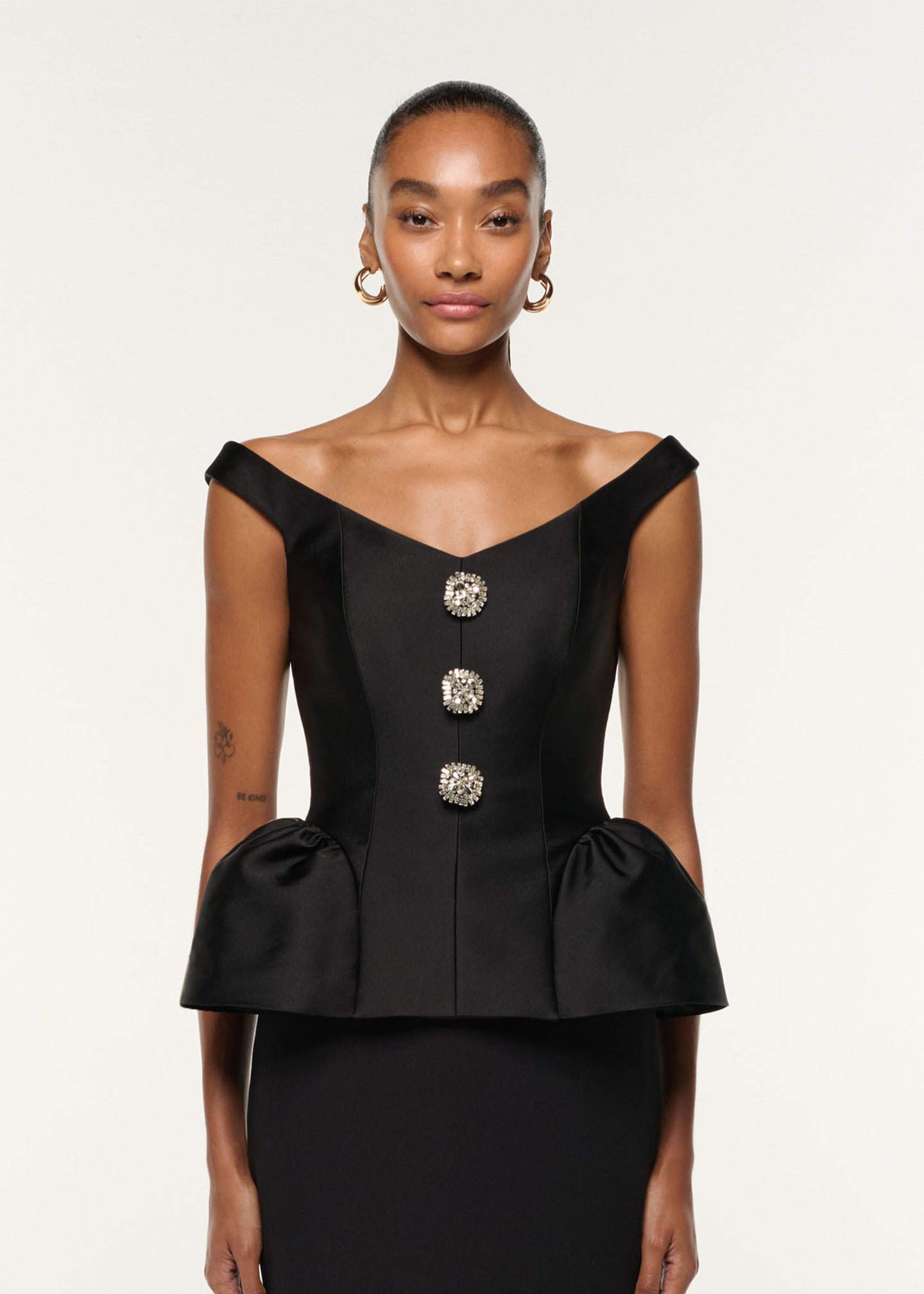 Close up of a model wearing the Crystal Button Peplum Taffeta Crepe Dress in Black