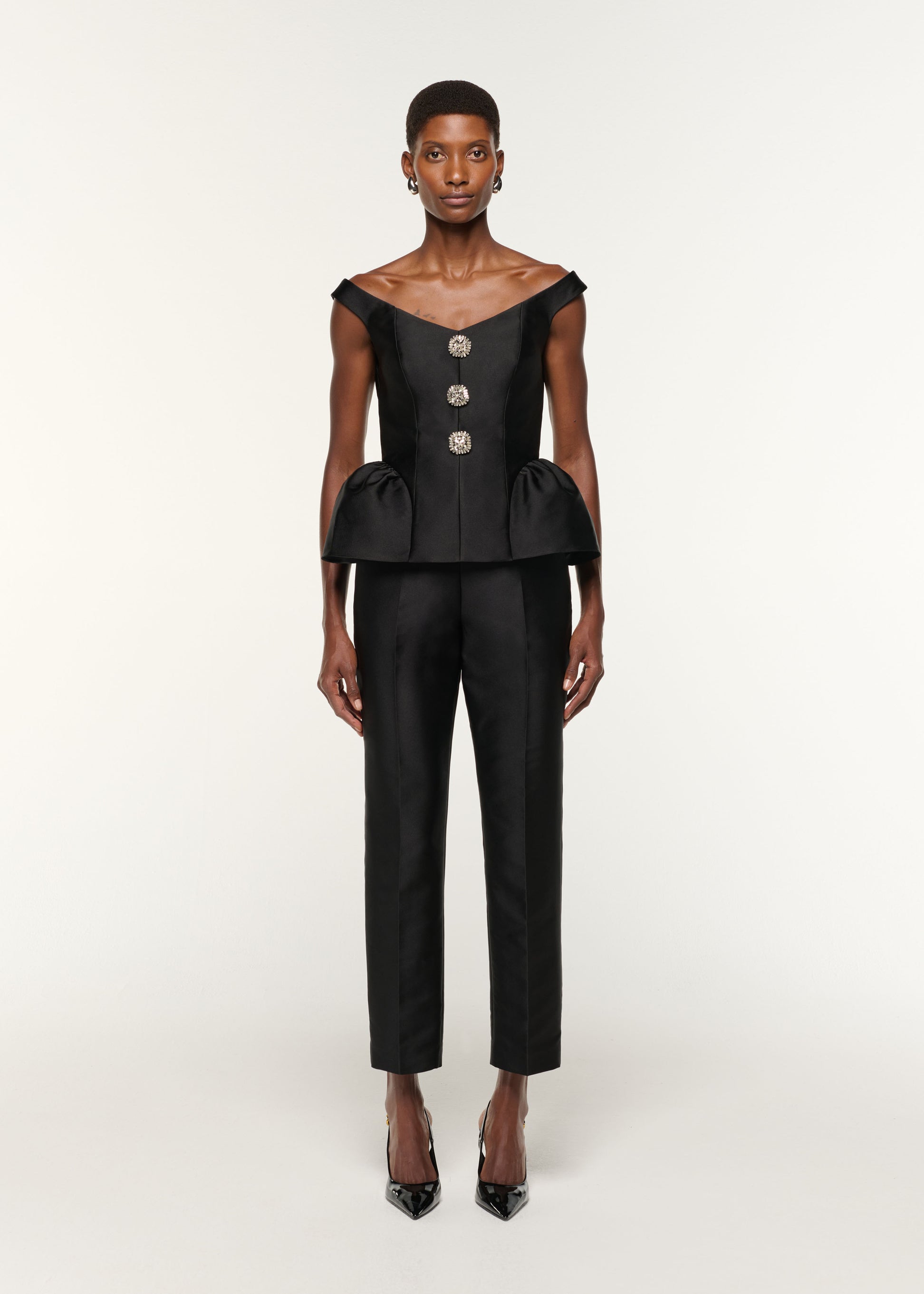 Front view of a model wearing the Crystal Button Peplum Taffeta Top in Black