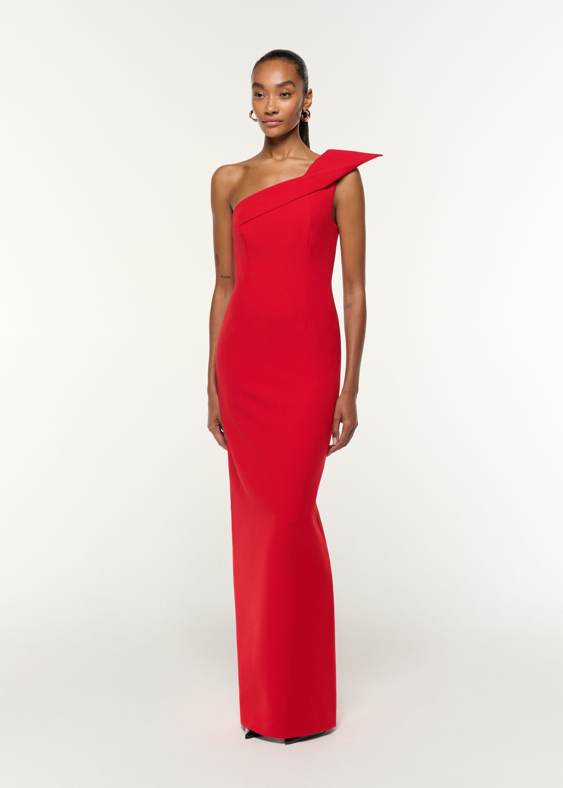 Side view of a model wearing the Structured Drape One Shoulder Crepe Gown in Red