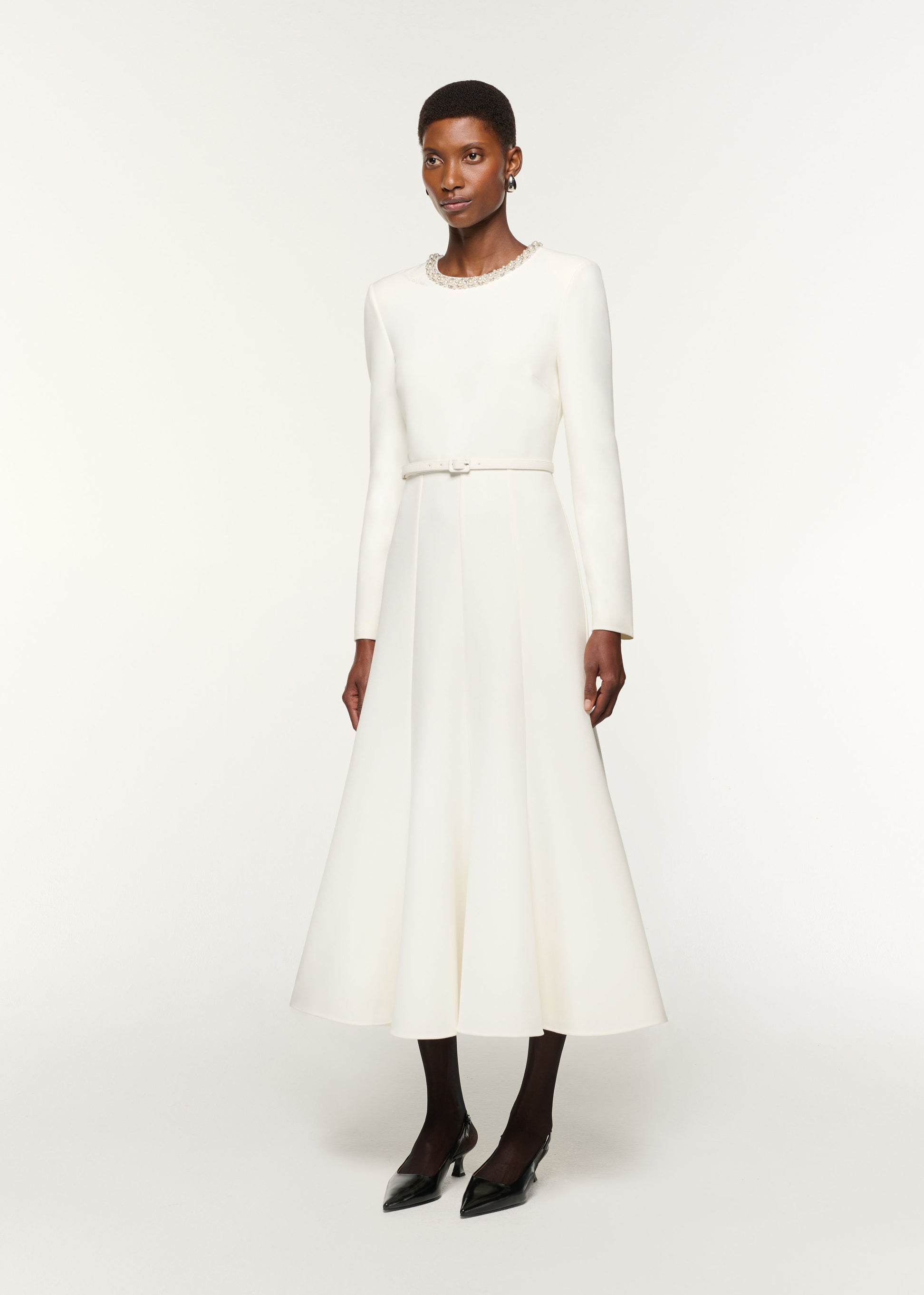 Side view of a model wearing the Crystal Neckline Crepe Dress in White