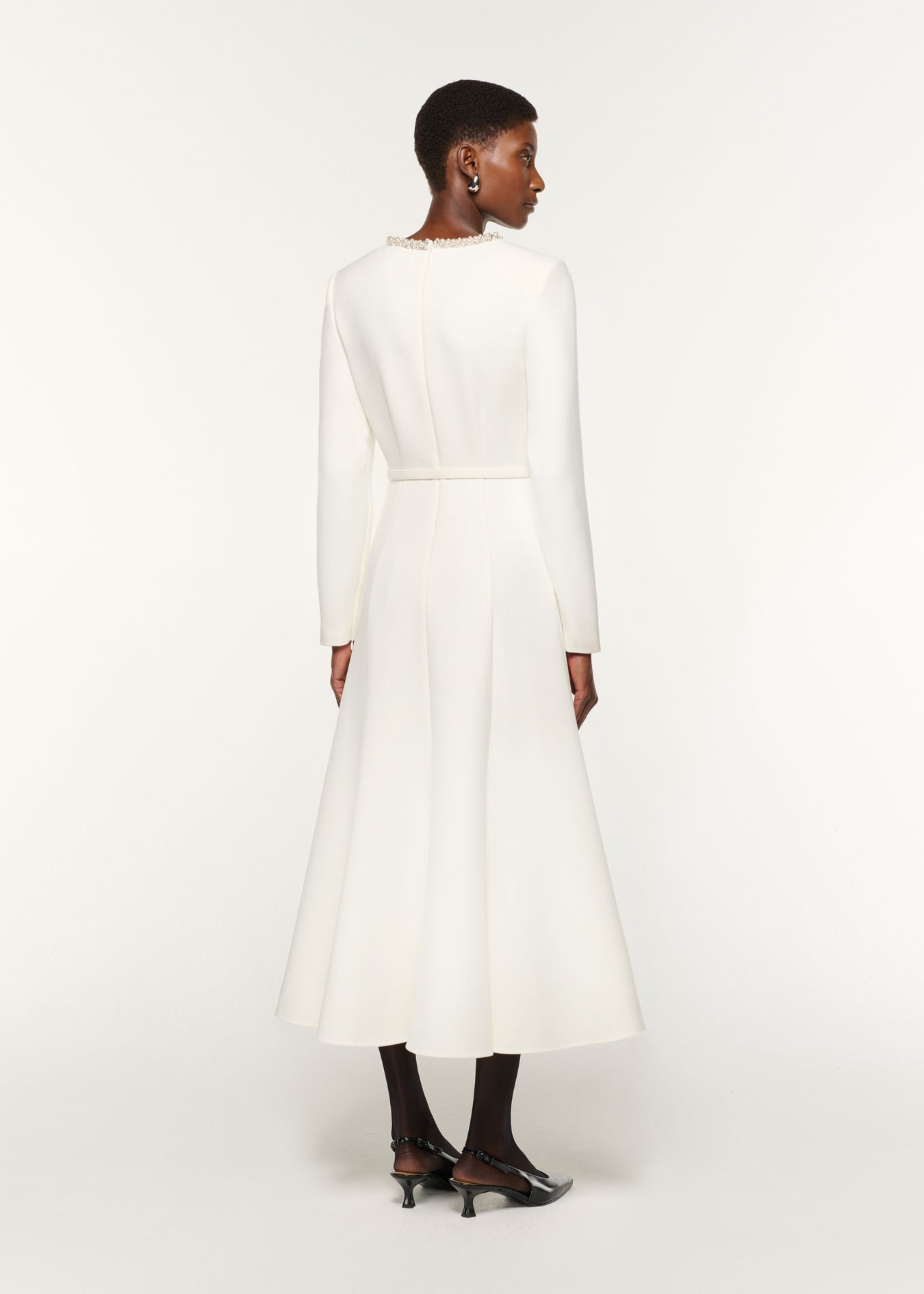 Back view of a model wearing the Crystal Neckline Crepe Dress in White