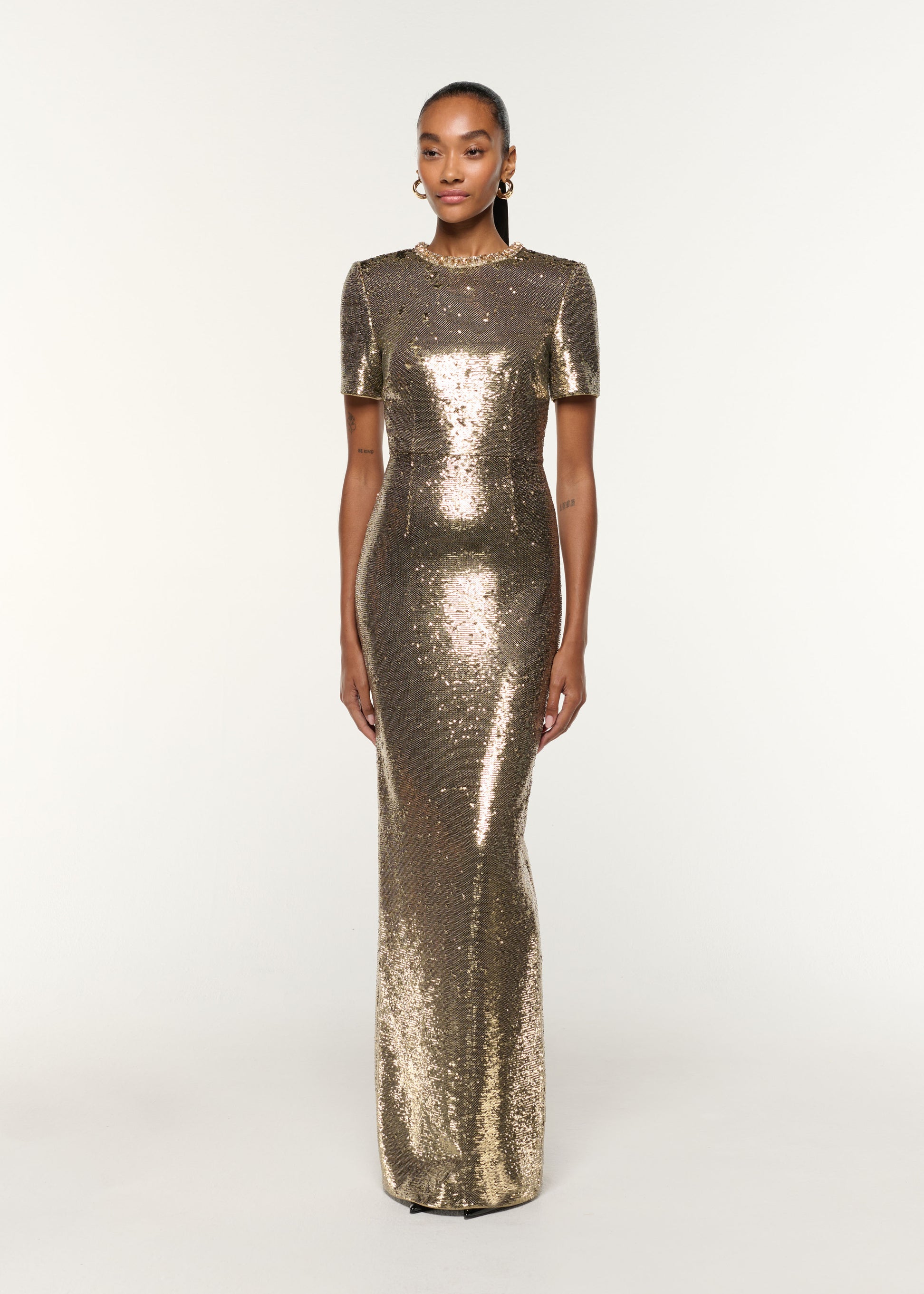 Side view of a model wearing the Crystal Neckline Sequin Column Gown in Gold