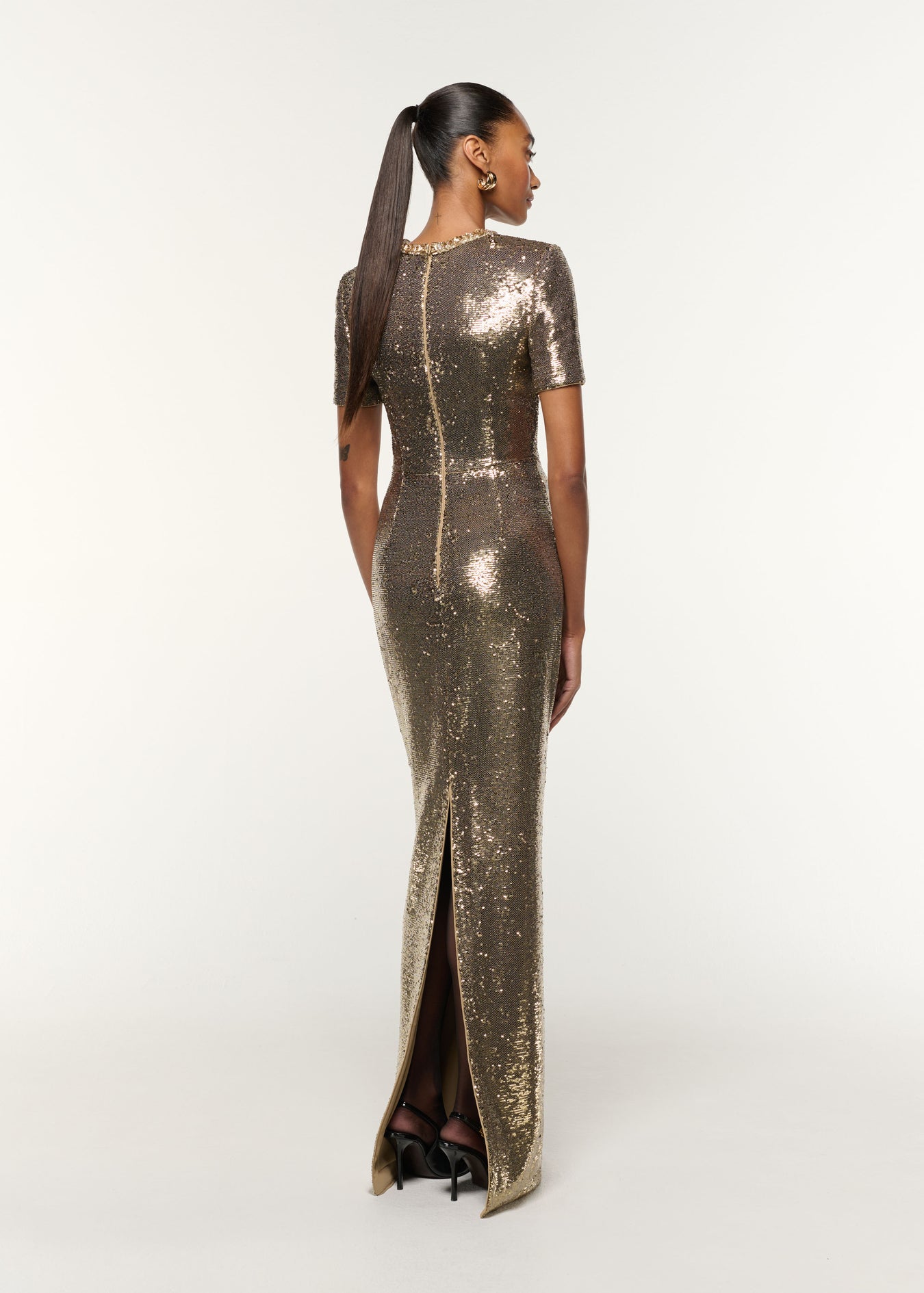 Back view of a model wearing the Crystal Neckline Sequin Column Gown in Gold